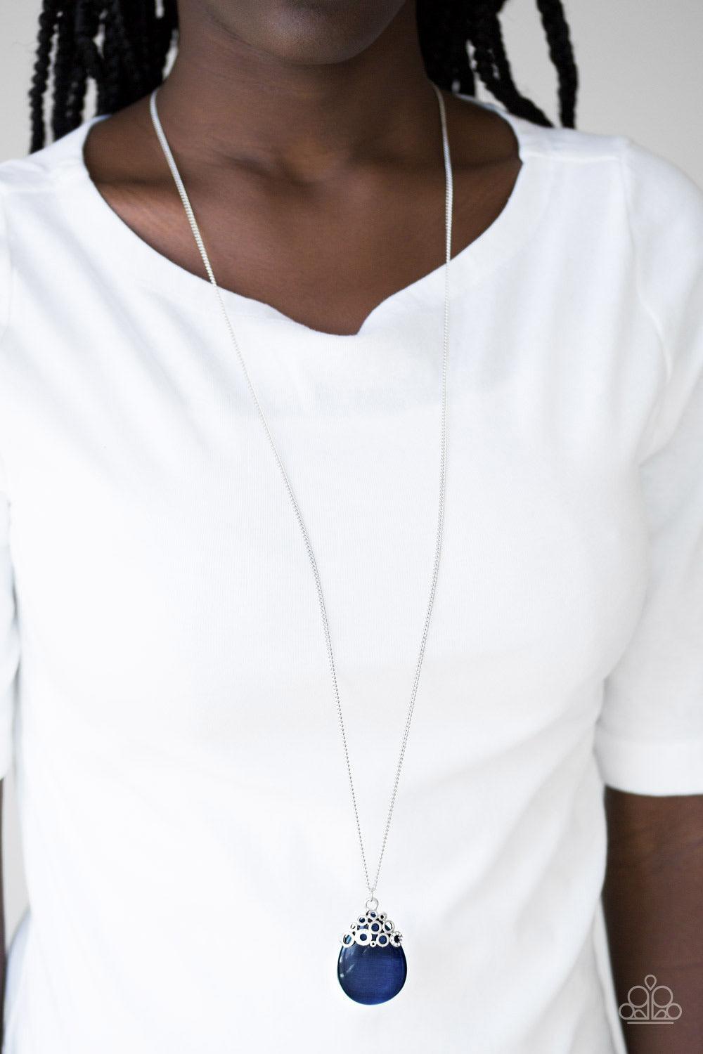 Paparazzi Accessories Nightcap And Gown - Blue Sporadically dotted in glittery white rhinestones, dainty silver circles join around the top of a glassy blue teardrop moonstone. The bubbly pendant swings from the bottom of a lengthened silver chain for a w