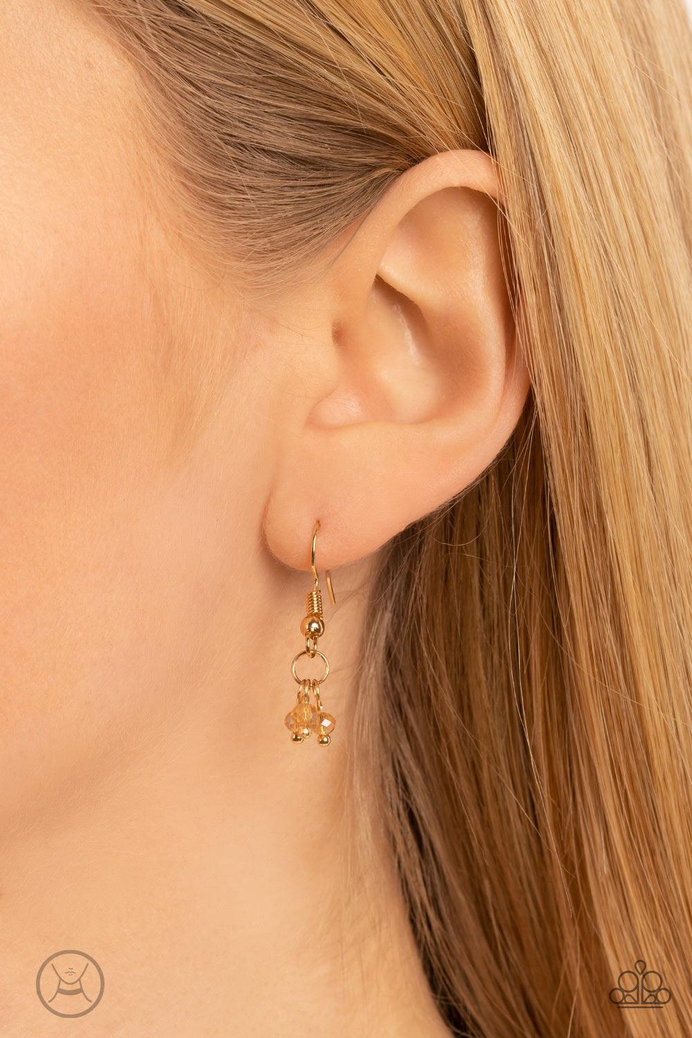 Paparazzi Accessories Mini MVP - Gold A dainty row of faceted white crystal-like beads delicately links around the neck, resulting in a golden glimmer. Features an adjustable clasp closure. Sold as one individual choker necklace. Includes one pair of matc