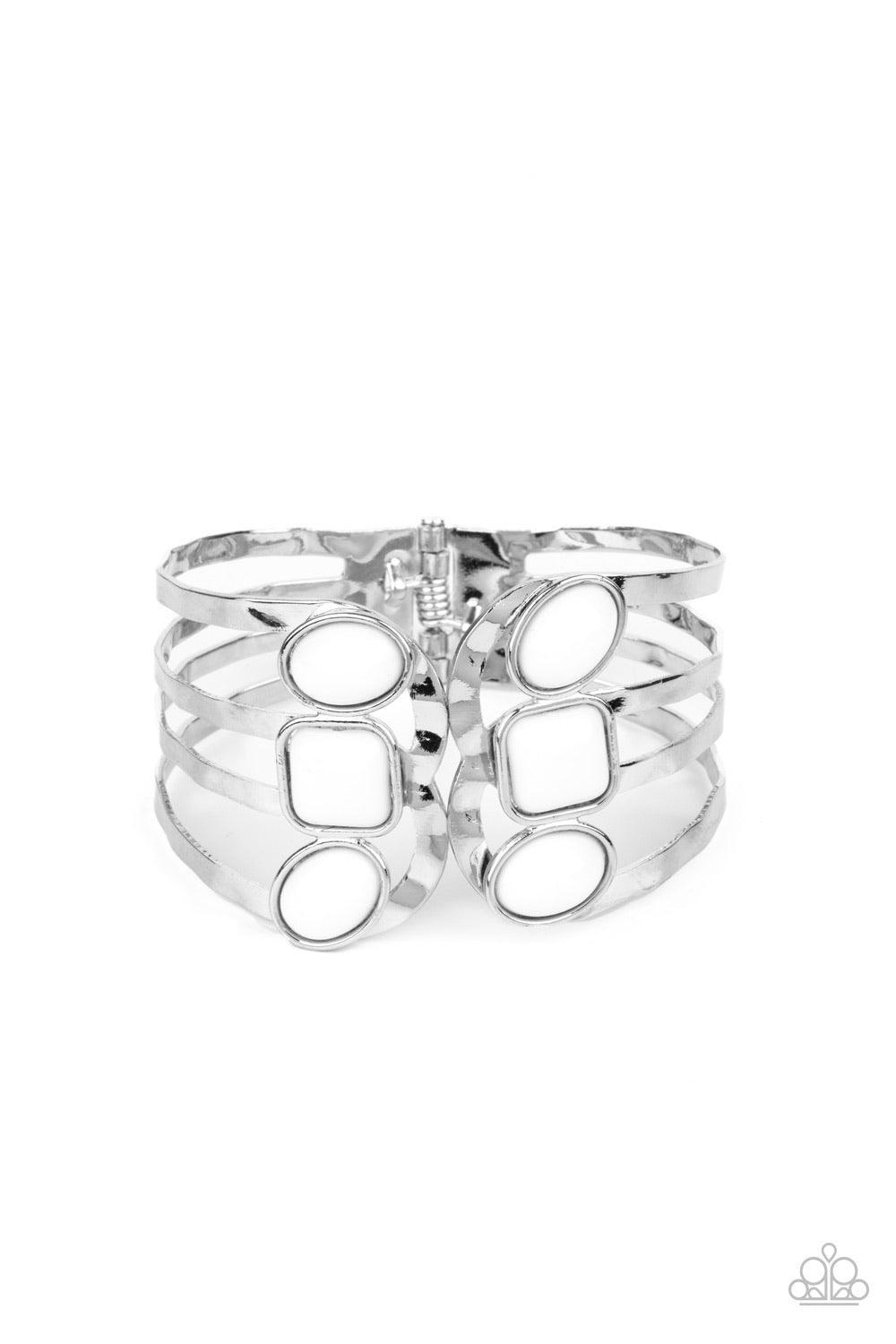 Paparazzi Accessories Mystified - White Dotted with oval and square white beads, hammered silver bars asymmetrically connect into two scalloped silver frames around the wrist, creating an adjustable open-faced cuff. Features a hinged closure. Sold as one