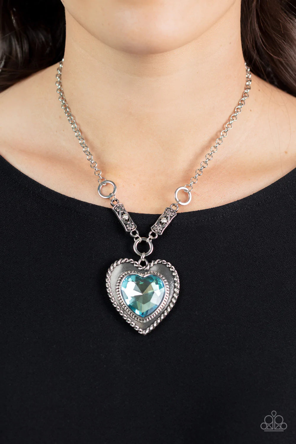 Paparazzi Accessories Heart Full of Fabulous - Blue Bordered in spun silver ribbons, an oversized blue heart gem is pressed into a silver heart frame below the collar. The flirtatious pendant attaches to silver rings and decorative silver frames dotted in