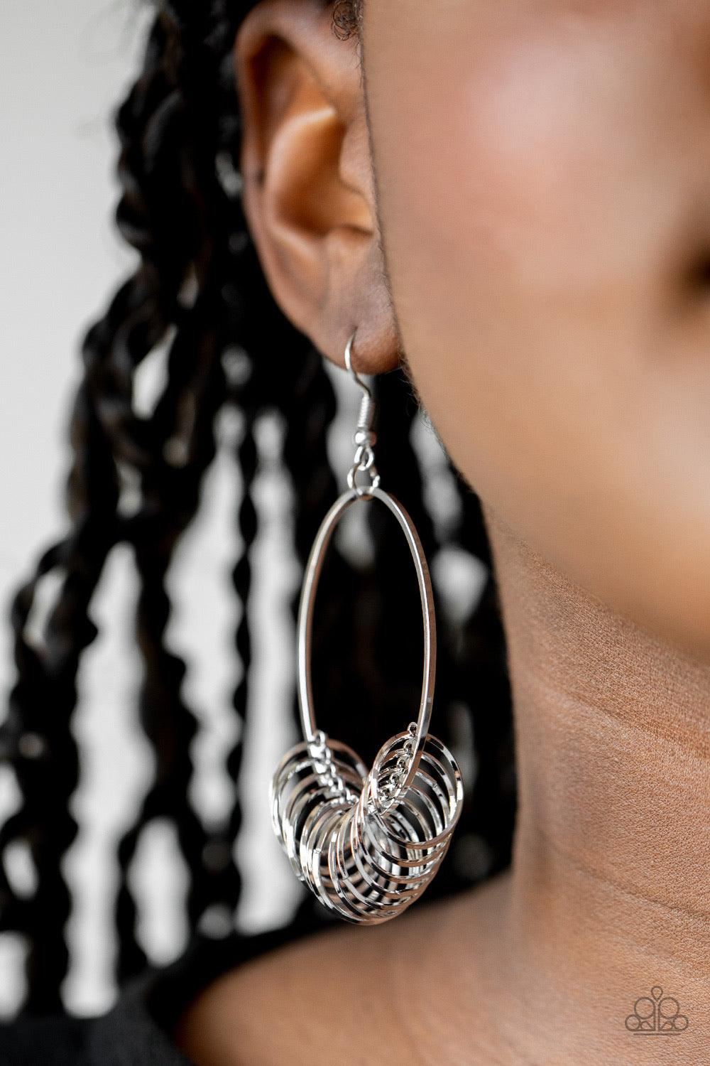 Paparazzi Accessories Halo Effect - Silver A collection of dainty silver rings are secured in place along the bottom of a silver oval frame, creating a dizzying fringe. Earring attaches to a standard fishhook fitting. Sold as one pair of earrings. Jewelry