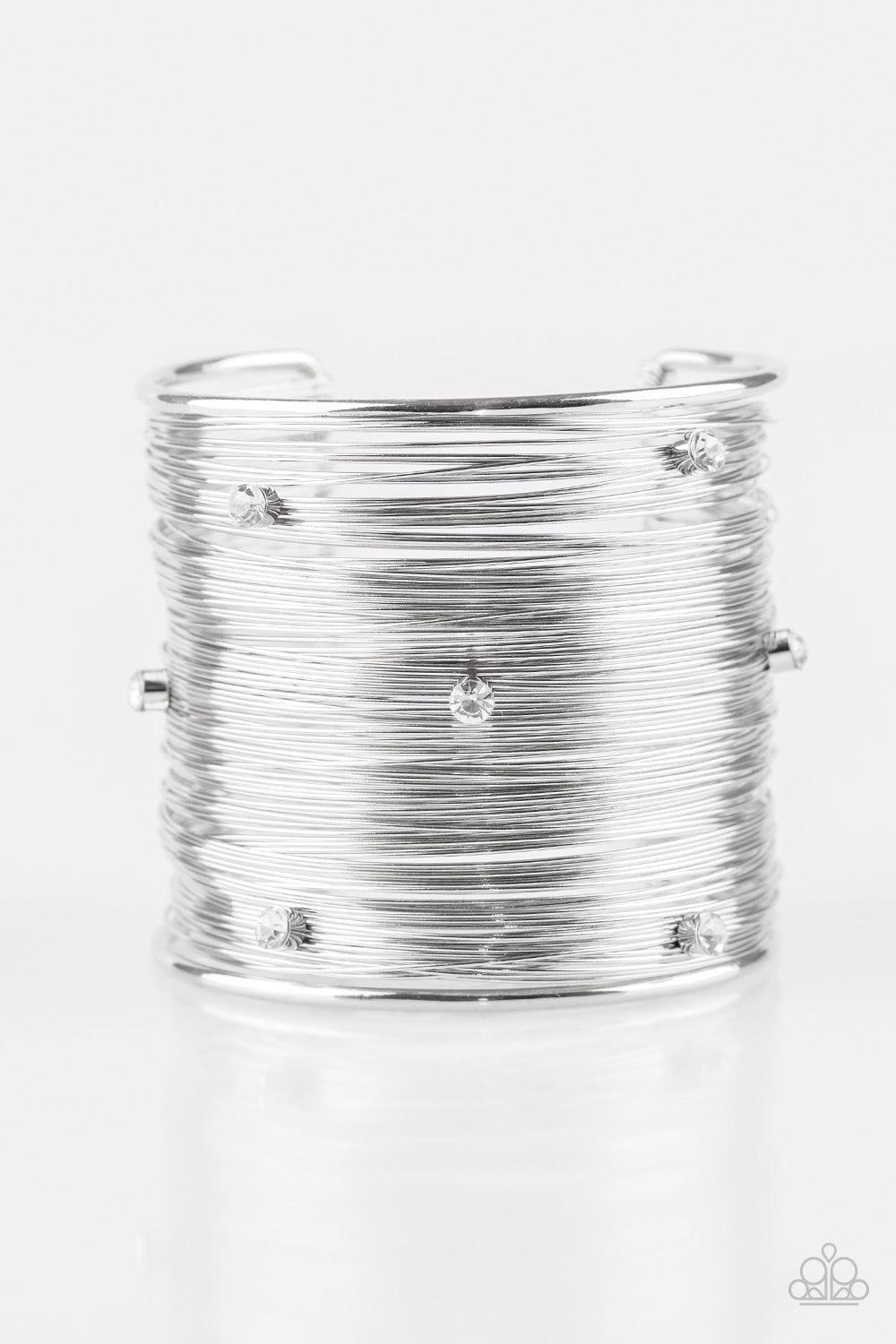 Paparazzi Accessories Professional Prima Donna - White Shimmery silver wires wrap back and forth along a silver frame, creating a bold cuff. Glassy white rhinestones are sprinkled across the dramatic cuff for a glamorous finish. Jewelry