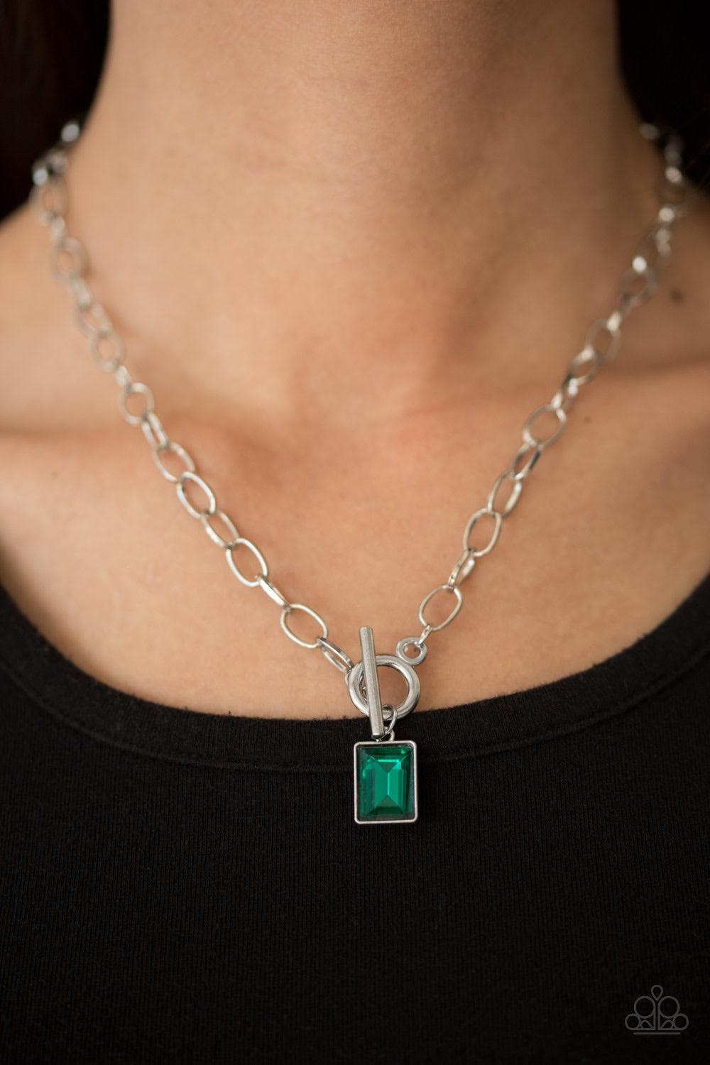 Paparazzi Accessories Wear it Like You Mean It! - Green Featuring a regal emerald-style cut, a glassy green rhinestone is pressed into a sleek silver frame. The glittery frame swings from the bottom of a bold silver chain, creating a glamorous pendant bel