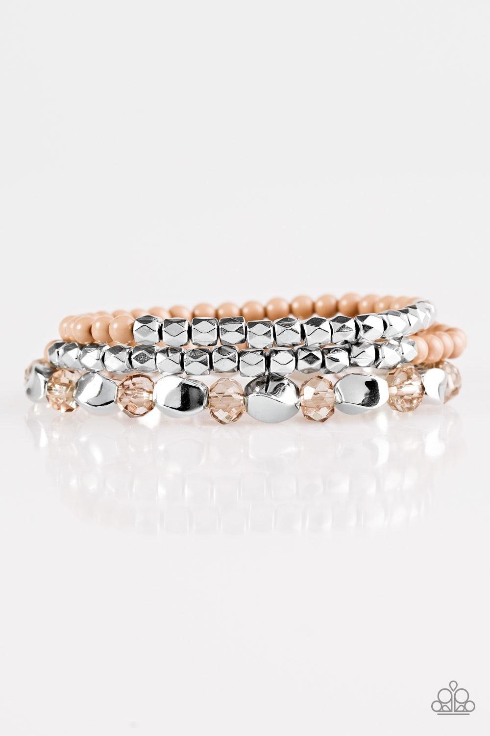 Paparazzi Accessories Beaded Bravado - Brown Varying in shape and shimmer, faceted silver beads, dainty brown beads, and glittery crystal-like beads are threaded along elastic stretchy bands, creating colorful layers across the wrist. Jewelry