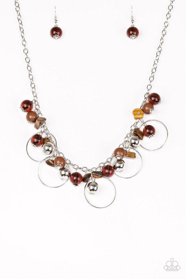 Paparazzi Accessories Mountain Mosaic - Brown Glassy brown, polished brown, and classic silver chains swing from the bottom of a shimmery silver chain. Infused with large silver hoops, bits of tranquil brown rock beading trickle between the beaded accent,