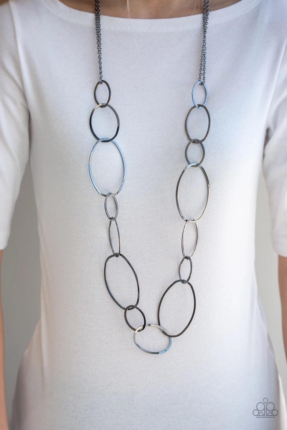 Paparazzi Accessories City Circuit - Black Swinging from doubled gunmetal chains, oversized asymmetrical hoops dramatically link across the chest for a refined industrial look. Features an adjustable clasp closure. Jewelry