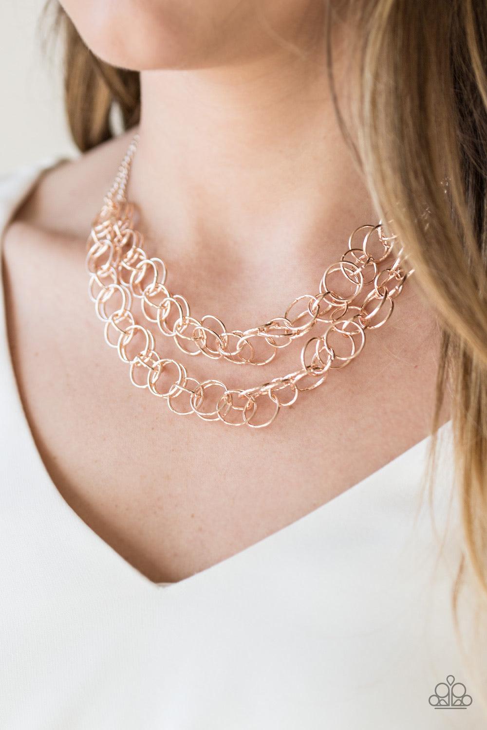 Paparazzi Accessories Circus Tent Tango - Gold Varying in size, rows of shiny rose gold rings interlock into two layered rows below the collar for an edgy industrial look. Features an adjustable clasp closure. Sold as one individual necklace. Includes one