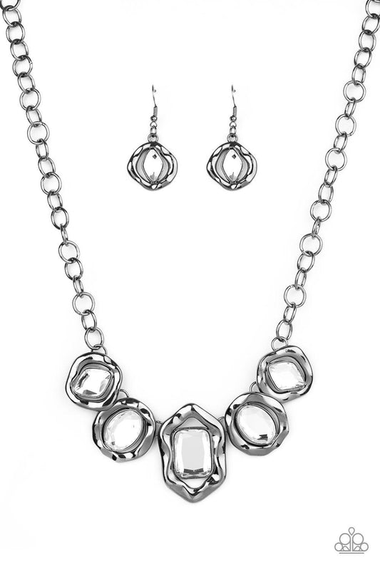 Paparazzi Accessories Celebrity Catwalk - Black Featuring imperfect gunmetal frames, a collection of diamond, oval, and emerald-cut white rhinestones connect below the collar in a blinding fashion. Features an adjustable clasp closure. Sold as one individ