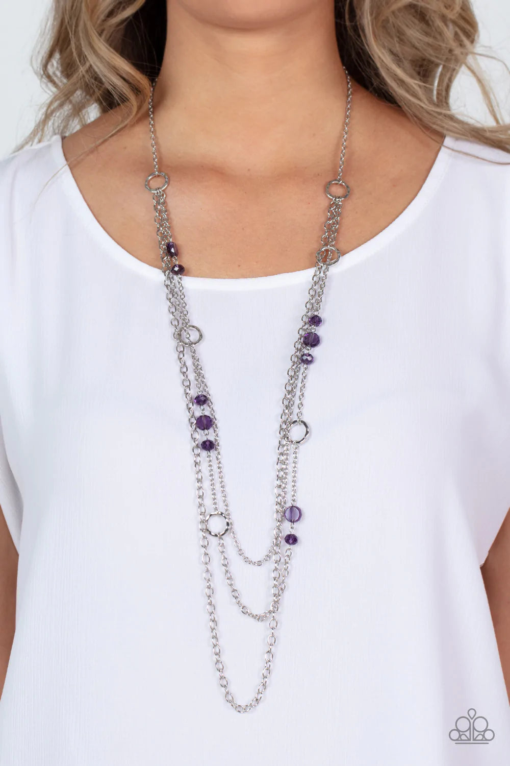 Paparazzi Accessories Starry-Eyed Eloquence - Purple Three mismatched silver chains elegantly drape across the chest. The centermost chain is adorned in textured silver hoops, purple crystal-like beads, and glassy purple gem accents for a sparkly finish.
