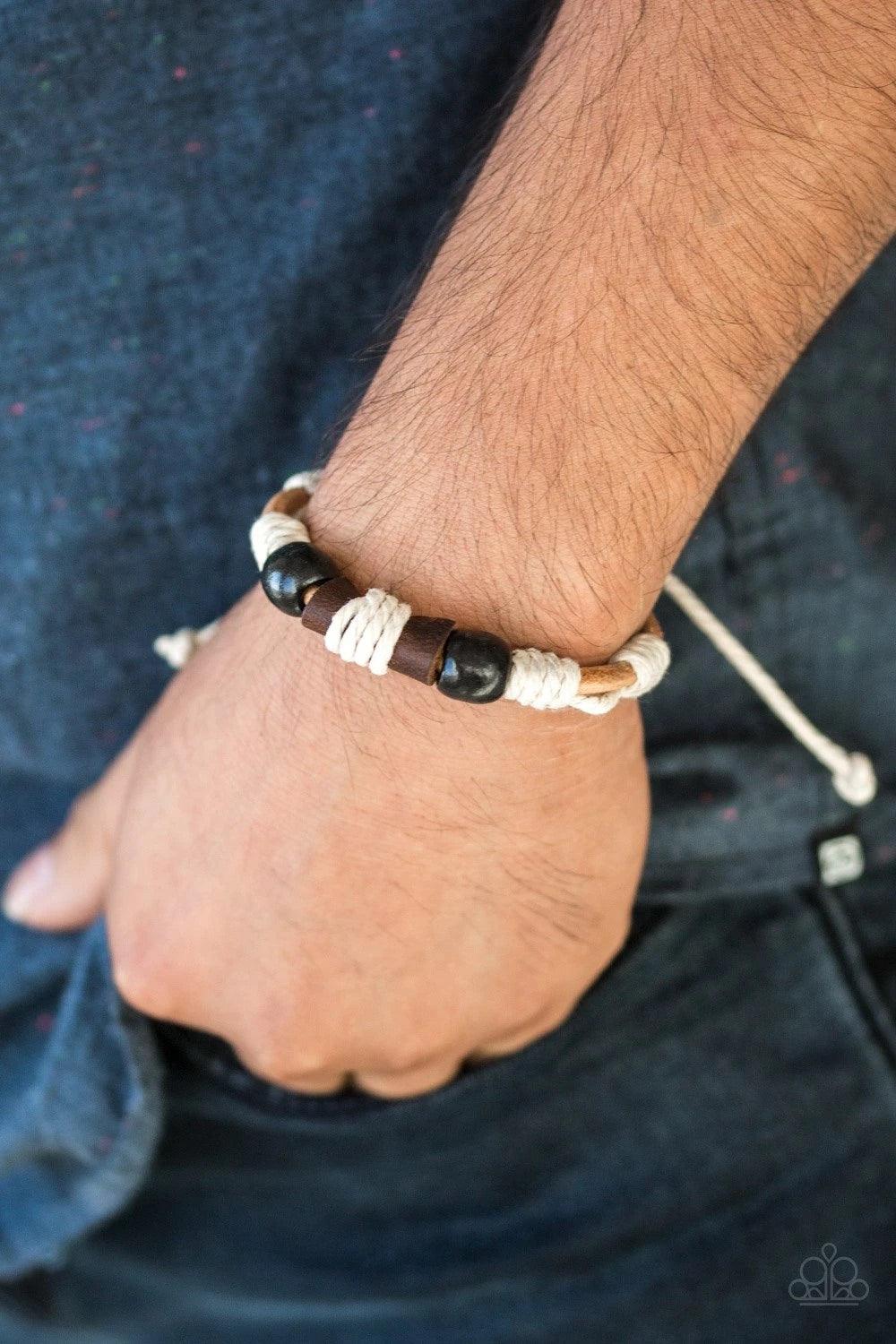 Paparazzi Accessories Back In The Backwoods - Black Earthy wooden beads and a piece of rolled leather is knotted across the front of a strand of brown suede cording for a seasonal flair. Features an adjustable sliding knot closure. Sold as one individual