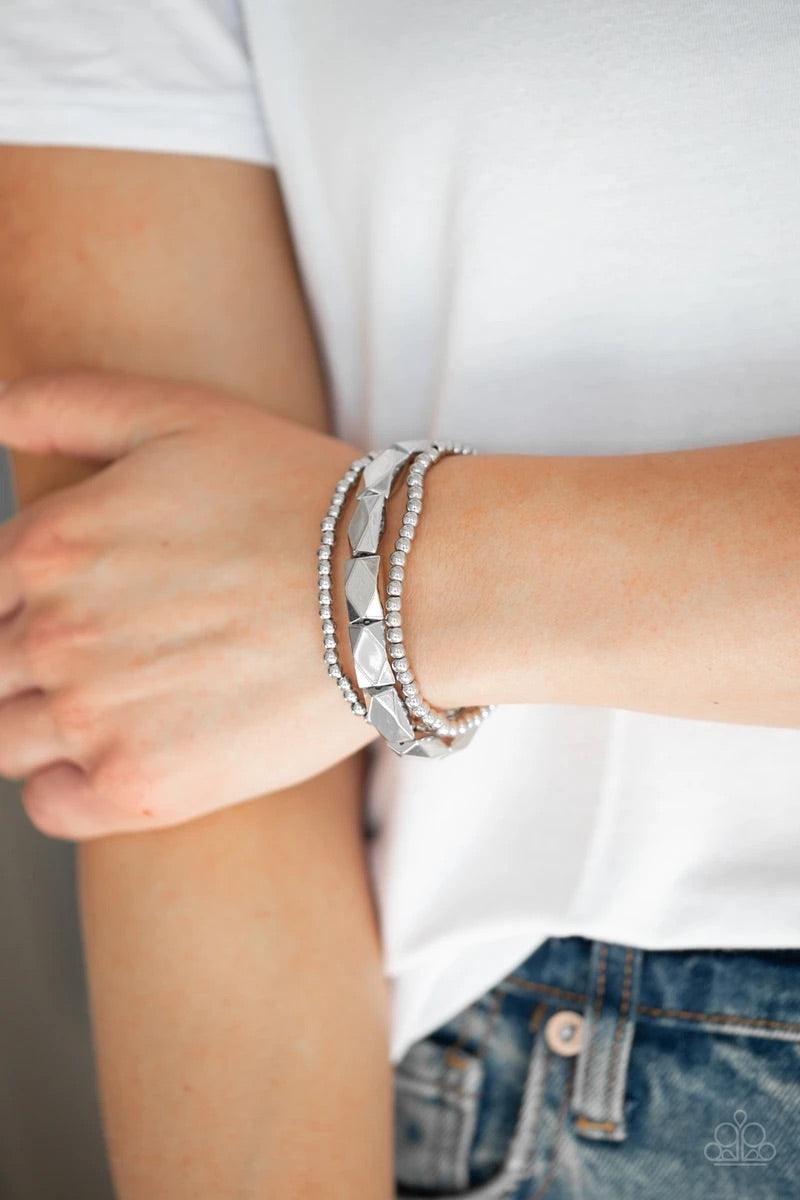 Paparazzi Accessories Metal Movement - Silver Dainty silver beads and faceted silver accents are threaded along stretchy bands and stacked across the wrist for a bold industrial look.Sold as one set of three bracelets. Jewelry