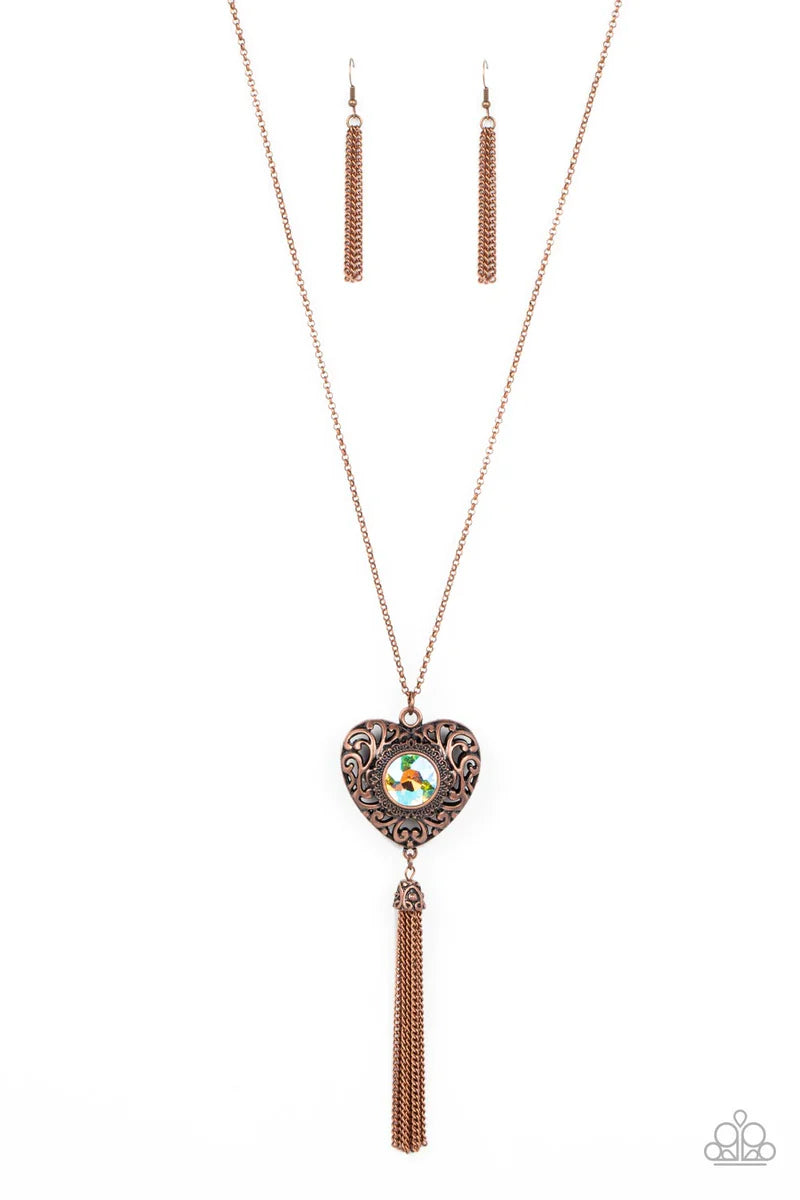Paparazzi Accessories Prismatic Passion - Copper A magical iridescent peach gem sparkles at the center of a 3-dimensional copper heart. Filled with vine-like filigree, the locket-inspired heart pendant glides along an extended copper chain while a shimmer