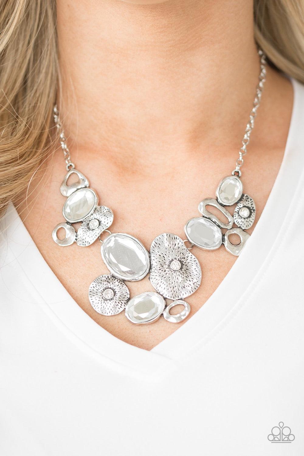 Paparazzi Accessories Grotto Grandeur - White Mismatched asymmetrical frames join below the collar. Sprinkled in dazzling white rhinestones, the delicately hammered silver frames connect with dramatic white gems for a glamorous finish. Features an adjusta