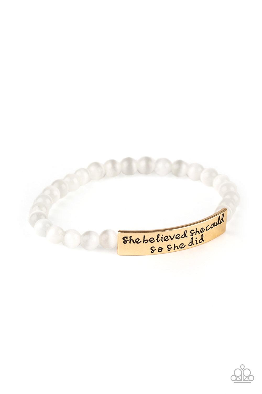 Paparazzi Accessories So She Did - Gold A collection of dainty white cat’s eye stone beads and a gold frame stamped in the inspirational phrase, “She believed she could, so she did”, are threaded along a stretchy band around the wrist for a whimsical fash