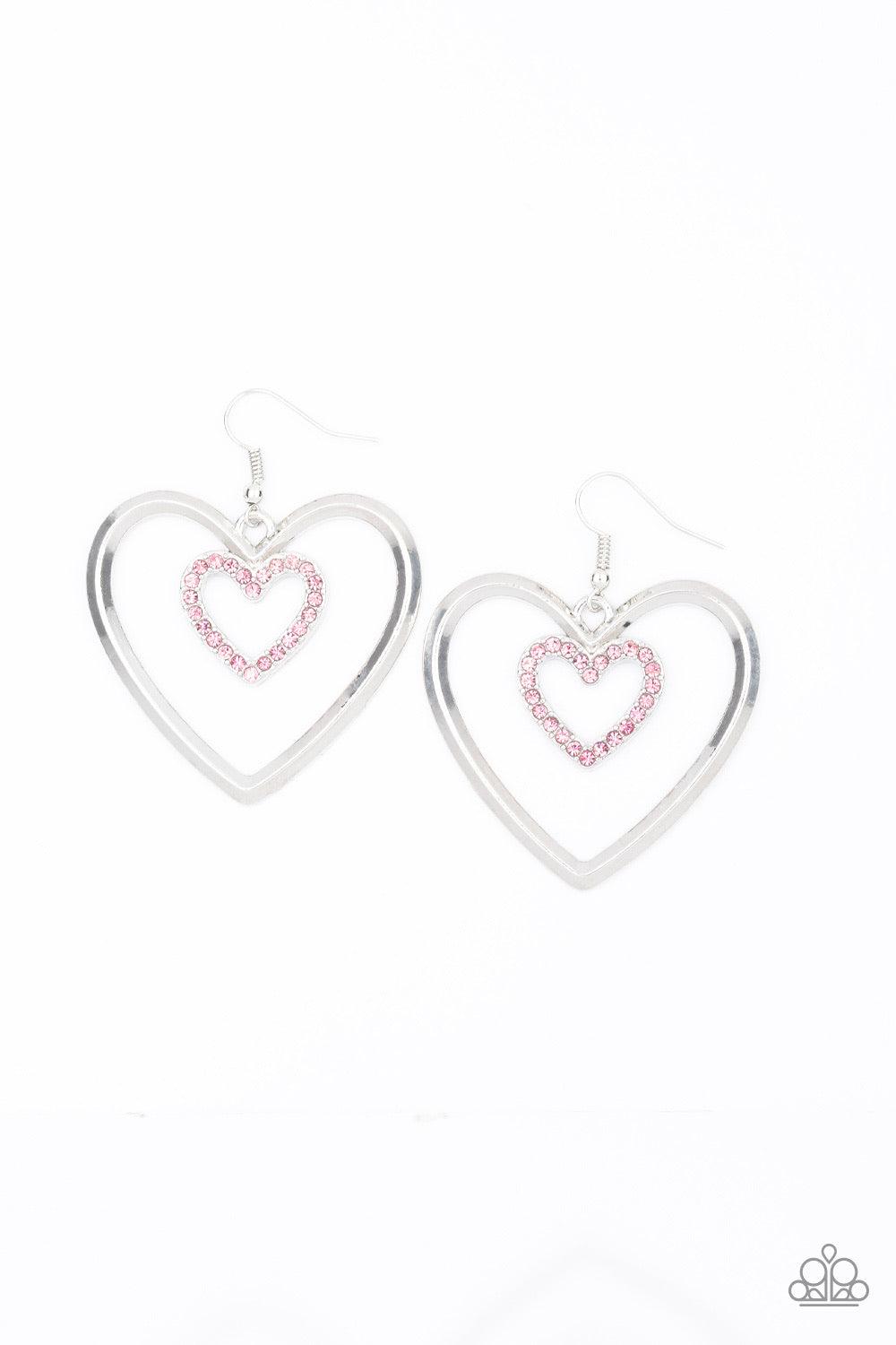 Paparazzi Accessories Heart Candy Coture - Pink A dainty pink rhinestone encrusted heart frame swings from the top of an oversized silver heart frame, creating a charming duo. Earring attaches to a standard fishhook fitting. Jewelry