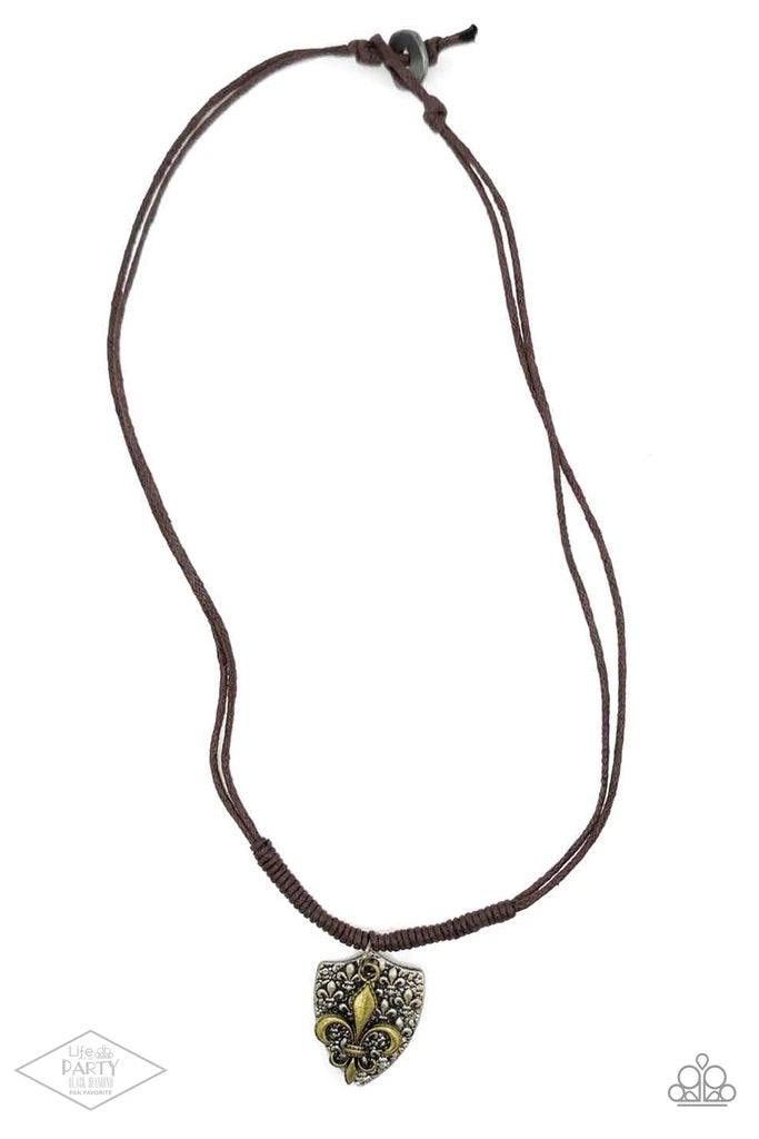 Paparazzi Accessories Shielded Simplicity - Brass An antiqued silver shield-shaped pendant embossed with a repeating fleur-de-lis pattern is paired with a brass fleur-de-lis charm at the bottom of doubled strands of brown cording. Sliding knots allow for