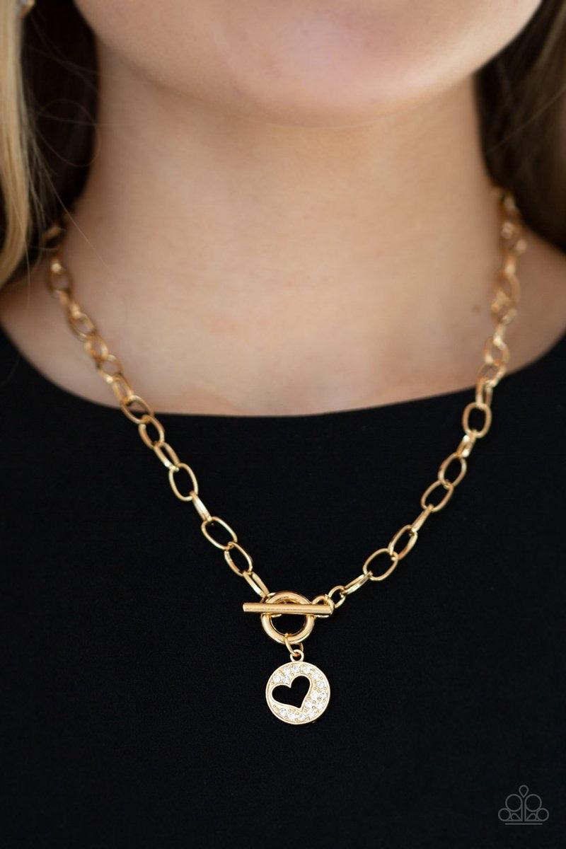 Paparazzi Accessories Heartbeat Retreat - Gold Radiating with glittery white rhinestones, an airy heart pendant swings from the bottom of a glistening gold chain below the collar for a flirty flair. Features a toggle clasp. Sold as one individual necklace