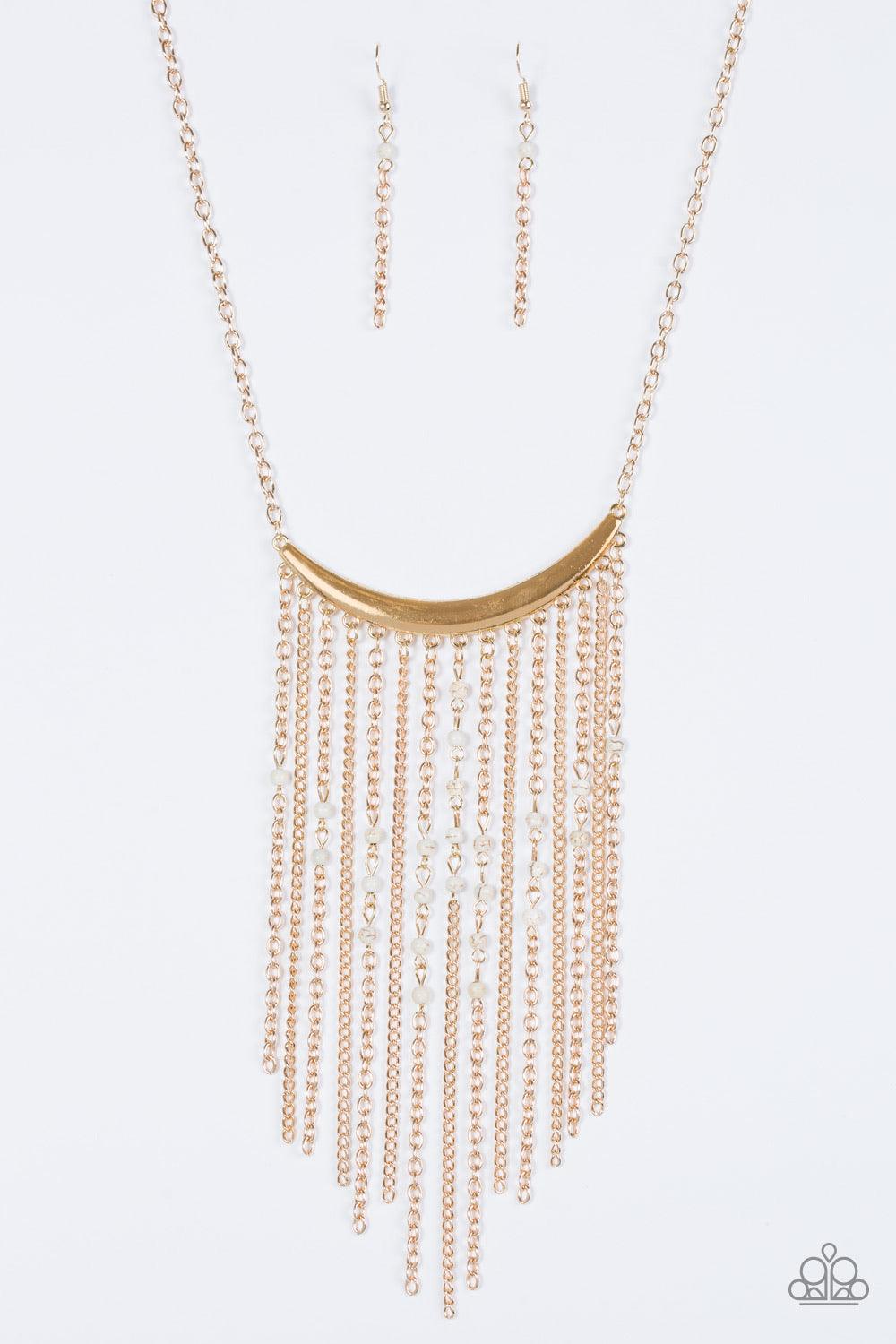 Paparazzi Accessories Runaway Rumba - Gold Glistening gold chains stream from the bottom of a shiny gold crescent, creating a bold tapered fringe down the chest. Dainty white stone beads sporadically trickle down the chains for a seasonal finish. Features