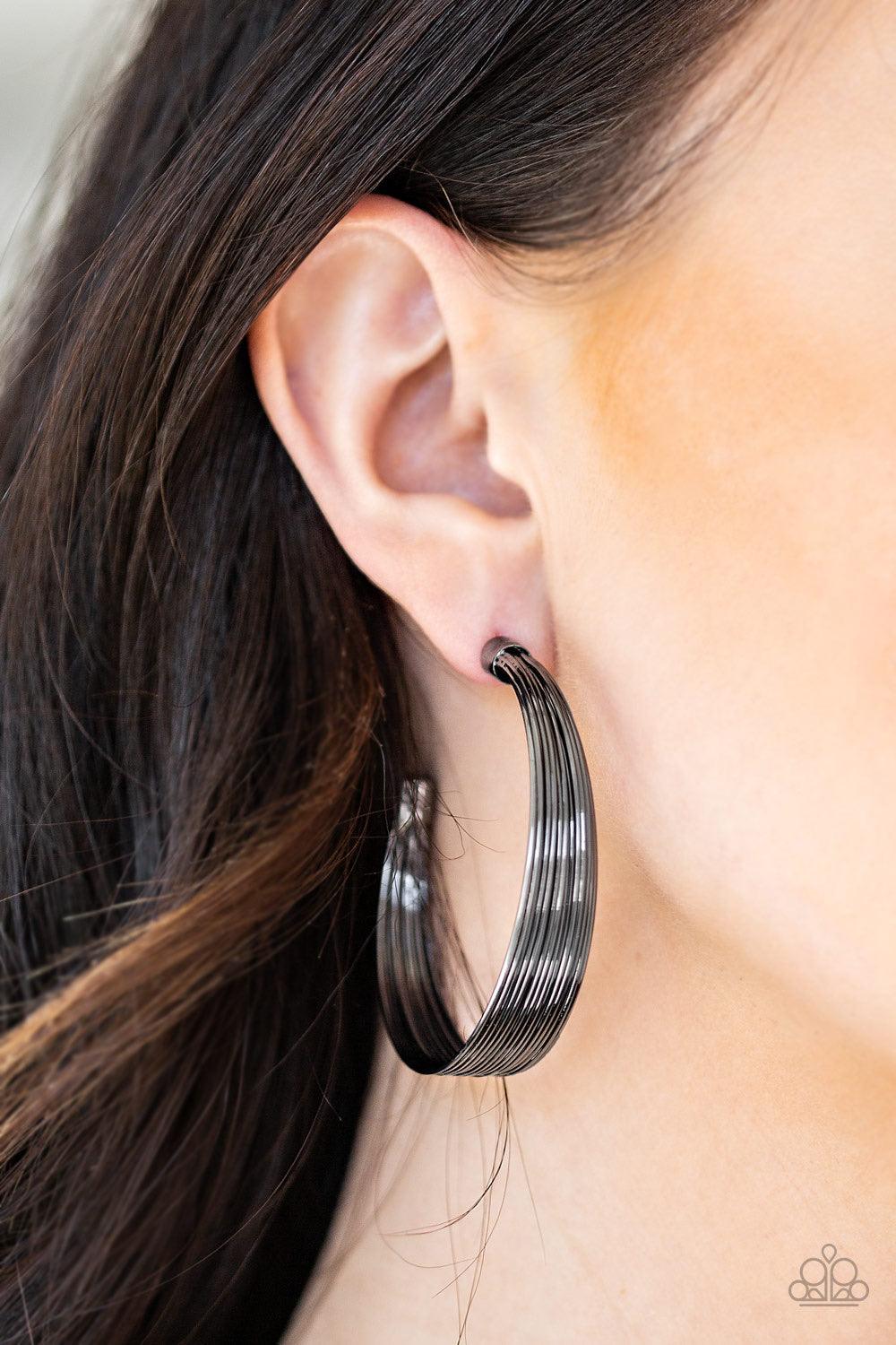 Paparazzi Accessories Live Wire - Black Attached to two shiny gunmetal/black fittings, wire after wire stacks into an edgy hoop. Earring attaches to a standard post fitting. Hoop measures 2" in diameter. Jewelry