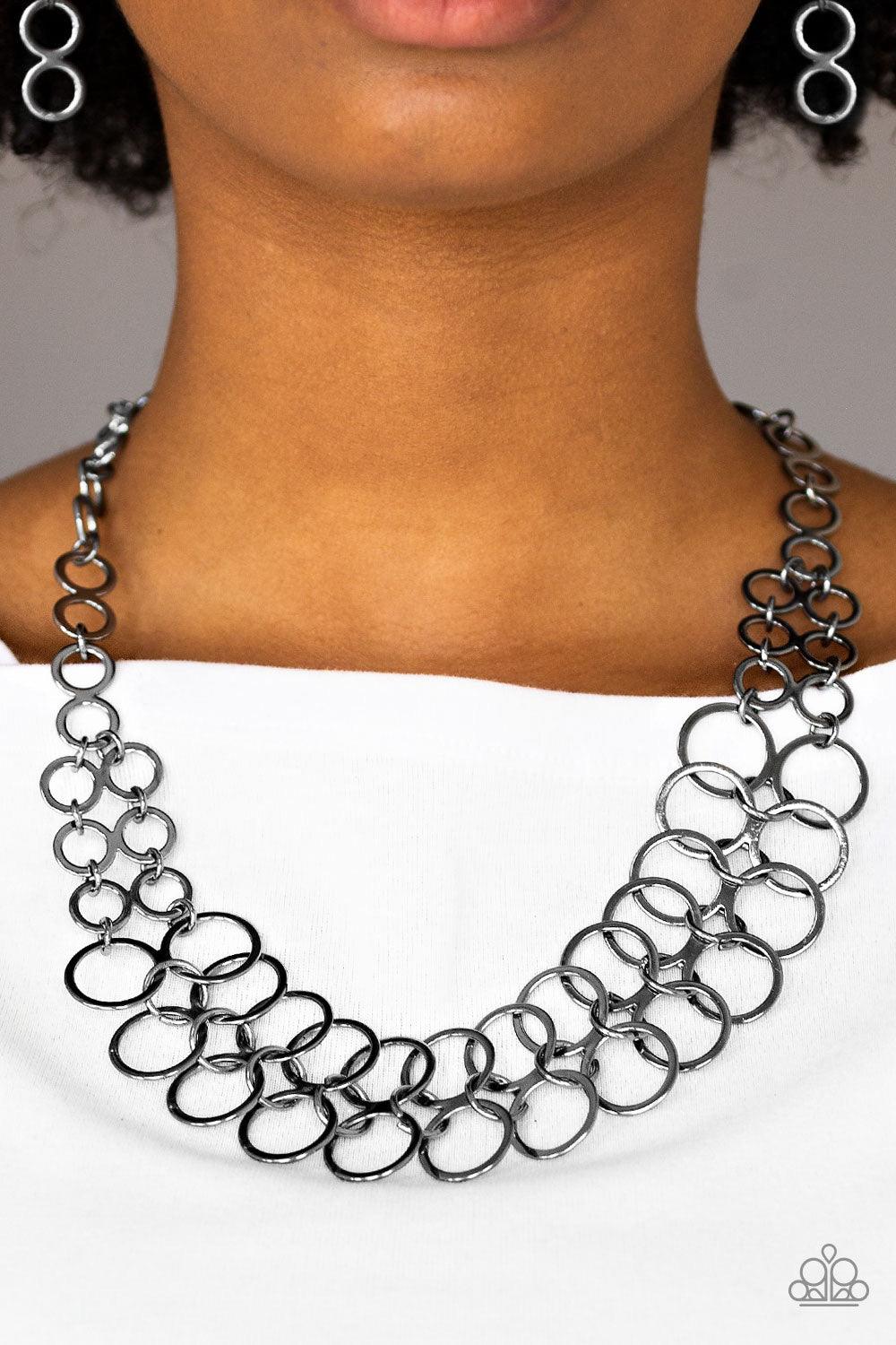Paparazzi Accessories Metro Maven - Black Gradually increasing in size near the center, double-linked gunmetal rings connect below the collar in a dramatic industrial fashion. Features an adjustable clasp closure. Sold as one individual necklace. Includes