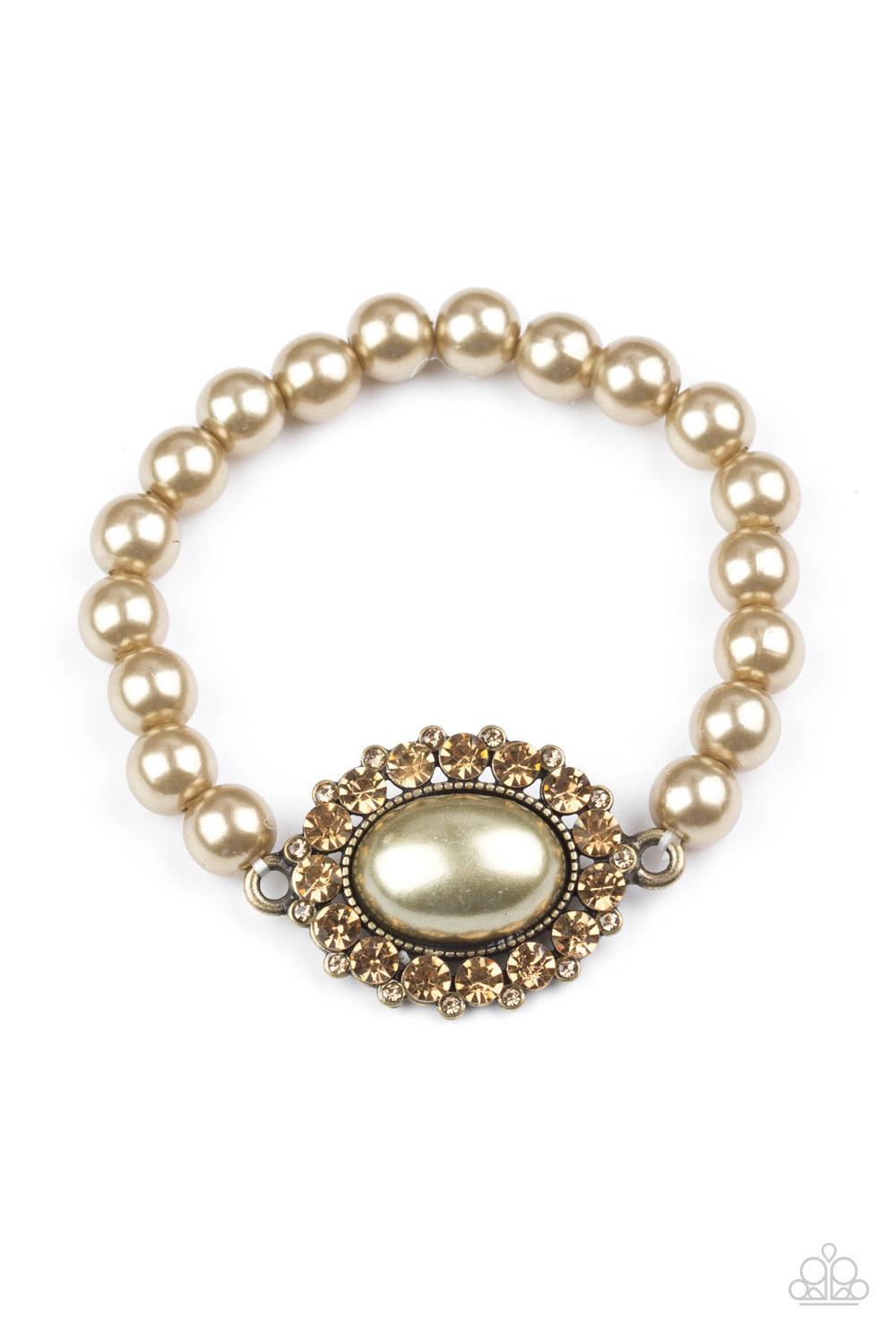 Paparazzi Accessories Starry-Eyed Starlet - Brass Pearly brass beads are threaded along an elastic stretchy band. A large brass pearl is pressed into the center of a topaz rhinestone encrusted frame, creating a dramatic centerpiece atop the wrist. Sold as
