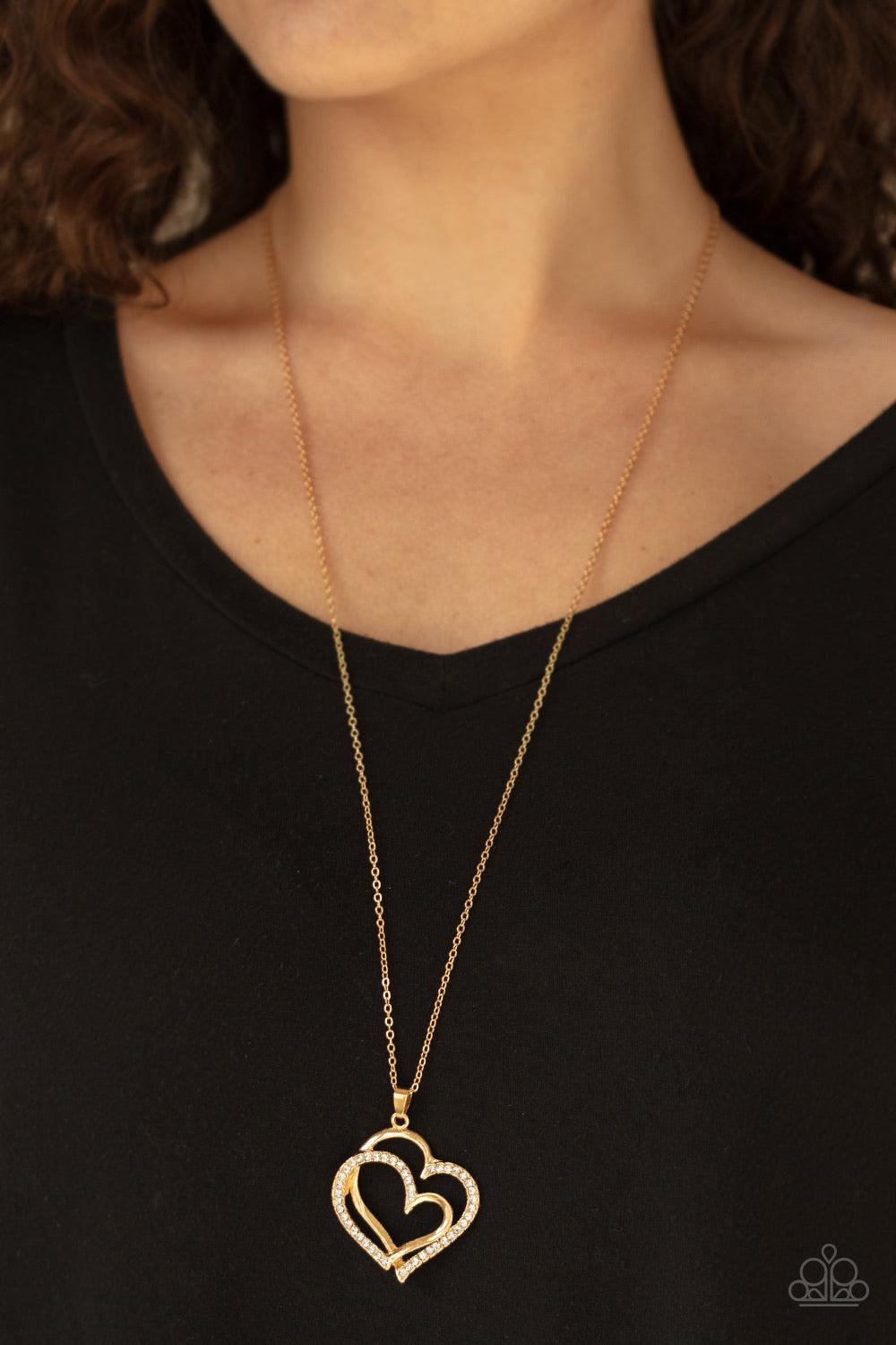 Paparazzi Accessories Lighthearted Luster ~Gold Encrusted in sections of glittery white rhinestones, two glistening gold hearts delicately join at the bottom of a lengthened gold chain for a charming look. Features an adjustable clasp closure.