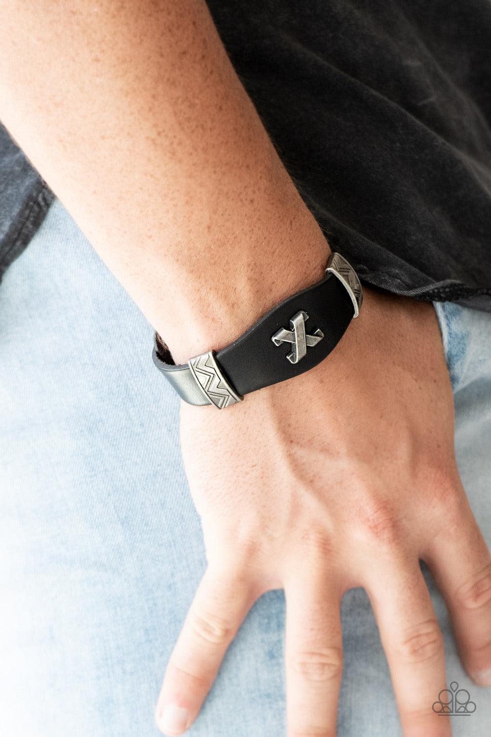 Paparazzi Accessories Tread Carey - Black Featuring ornate metallic accents, an antiqued crisscross frame embellishes the center of a black leather band for an edgy urban look. Features an adjustable snap closure. Jewelry