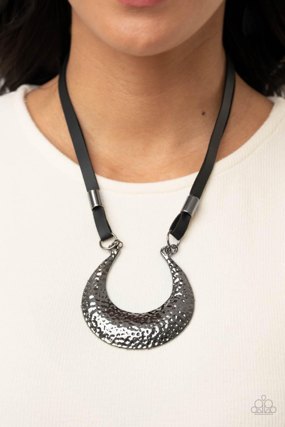 Paparazzi Accessories Majorly Moonstruck - Black Infused with glistening gunmetal beads, strips of black leather link to an oversized half moon pendant that is hammered in a blinding gunmetal finish, creating an edgy statement piece below the collar. Feat