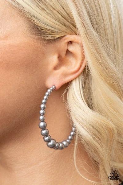Paparazzi Accessories Glamour Graduate - Silver Gradually increasing in size at the center, a classic row of pearly silver beads are threaded along an oversized hoop for a posh finish. Earring attaches to a standard post fitting. Hoop measures approximate