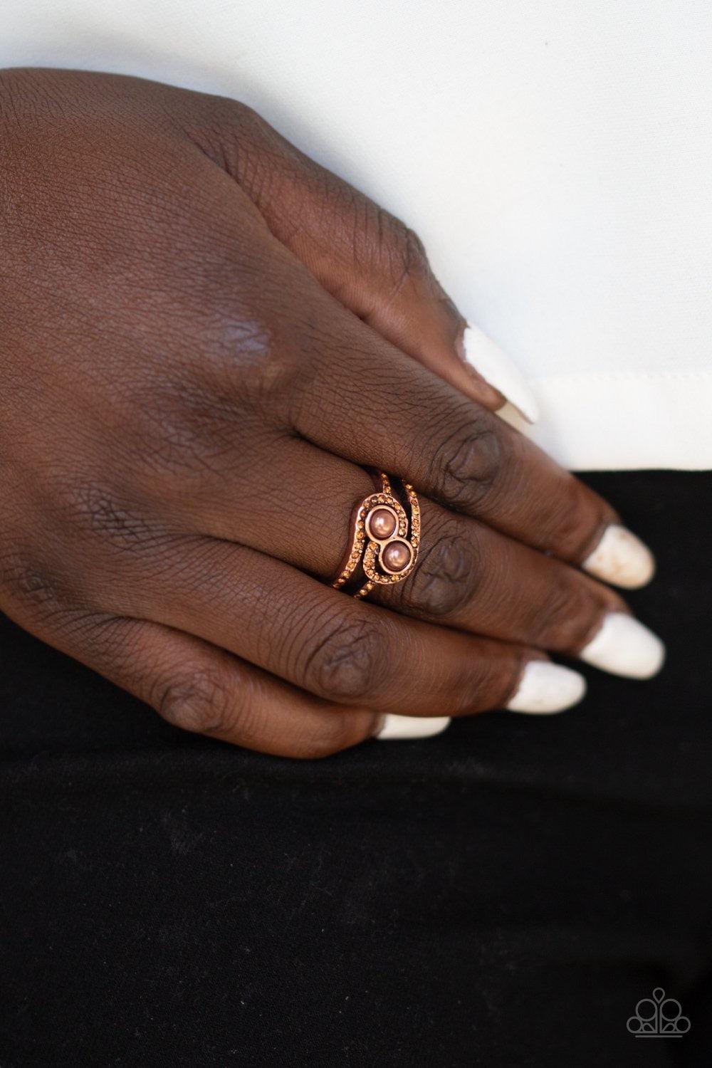 Paparazzi Accessories Collect Up Front - Copper Glittery topaz rhinestone encrusted bands swirl around a pair of coppery pearls for a refined look. Features a dainty stretchy band for a flexible f Jewelry