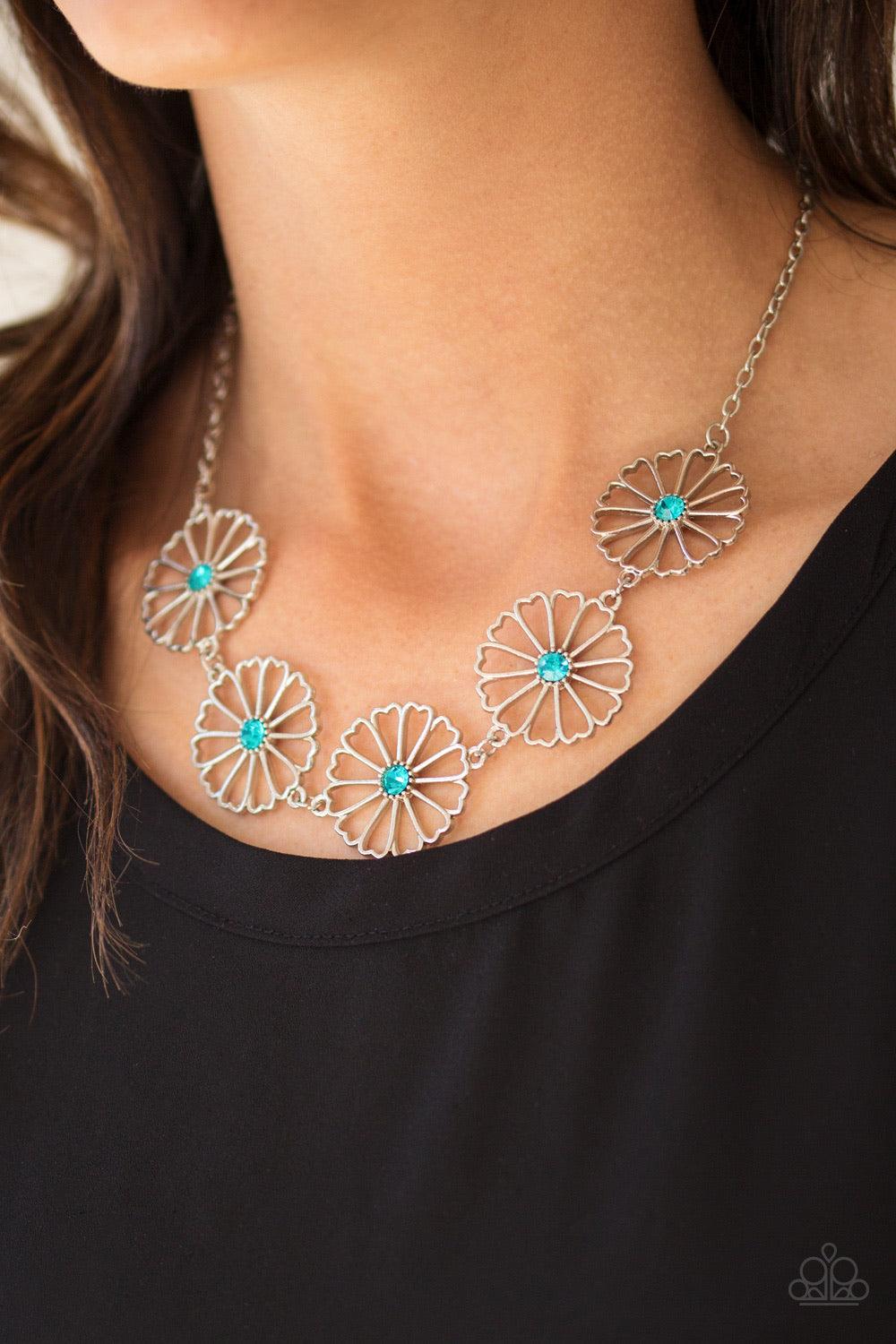 Paparazzi Accessories Daffodil Garden - Blue Stenciled silver floral charms link below the collar. Glittery blue rhinestones dot the floral centers, adding a whimsical finish to the airy palette. Features an adjustable clasp closure. Sold as one individua