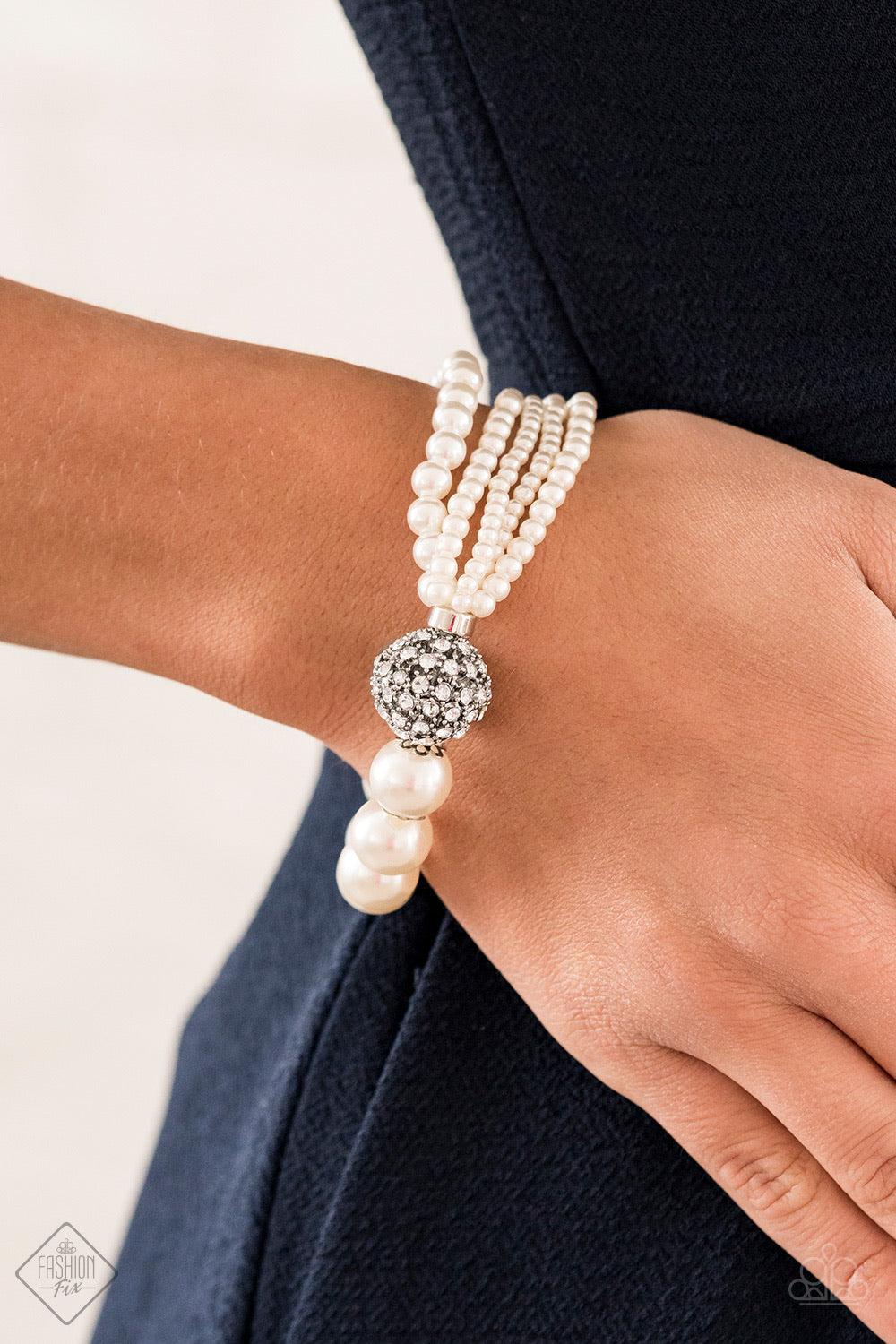 Paparazzi Accessories Show Them The DIOR! - White Featuring comfortable stretchy bands, a white rhinestone-encrusted silver bead connects strands of mismatched white pearls and a single strand of classic white pearls around the wrist in a timeless twist.