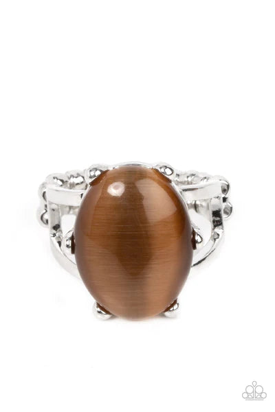 Paparazzi Accessories Enchantingly Everglades - Brown An oval brown cat's eye gemstone sits atop a pronged silver frame along two layered silver bands, resulting in an enchanting centerpiece atop the finger. Features a stretchy band for a flexible fit. So