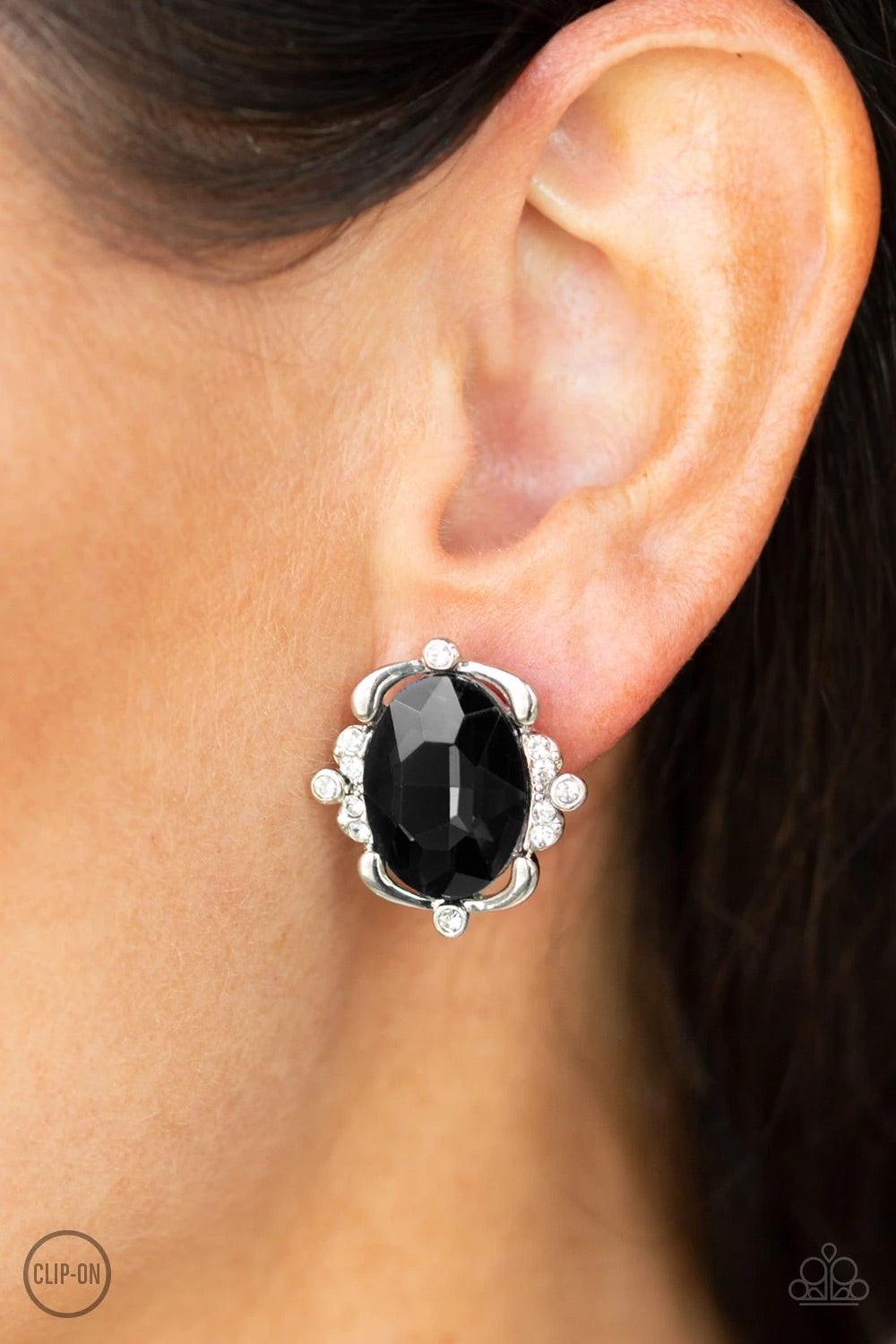 Paparazzi Accessories Regally Radiant ~Black *Clip-On Sporadically dotted in sections of glassy white rhinestones, shimmery ribbons of silver gently fold around a dazzling black emerald-style gem center for a regal look. Earring attaches to a standard cli