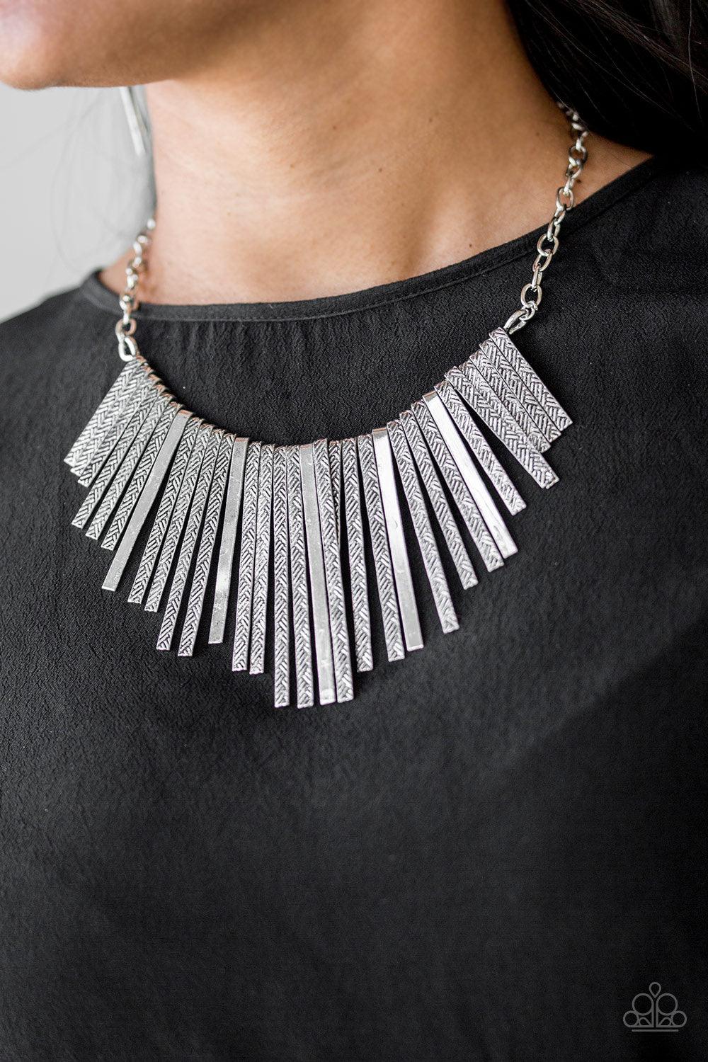 Paparazzi Accessories Welcome To The Pack - Silver Embossed in edgy linear patterns, flat silver rods alternate with plain silver rods below the collar, creating a fiercely tapered fringe. Features an adjustable clasp closure. Sold as one individual neckl