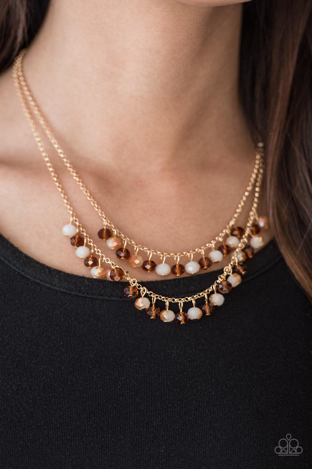 Paparazzi Accessories Starlight Sailing - Gold Brushed in an iridescent sheen, faceted white and brown crystal-like beads swing from the bottom of layered gold chains, creating a bold fringe below the collar. Features an adjustable clasp closure. Sold as