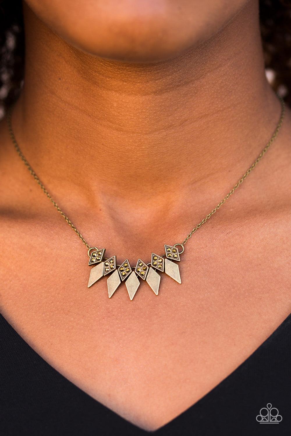 Paparazzi Accessories Over The Edge - Brass Encrusted in glittery aurum rhinestones, dainty diamond-shaped frames give way to matching brass frames, creating an edgy fringe below the collar. Features an adjustable clasp closure. Sold as one individual nec