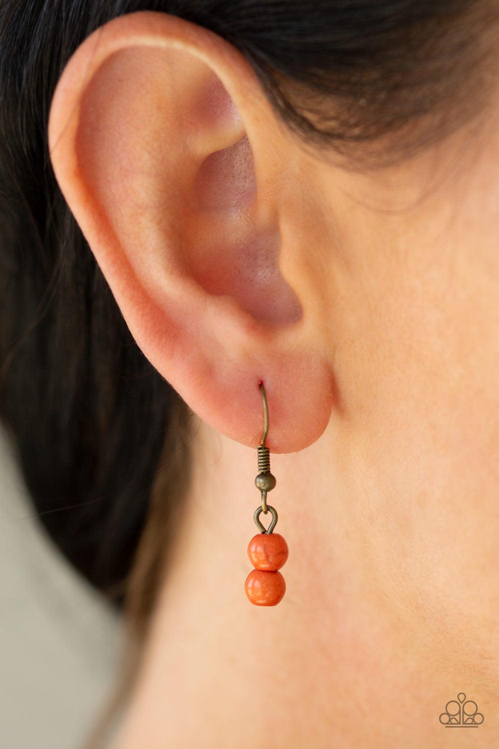 Paparazzi Accessories Terra Trails - Orange Strands of refreshing orange stones and textured brass accents are threaded along invisible wires streaming from the bottom of dainty brass chains, creating earthy layers below the collar. Features an adjustable
