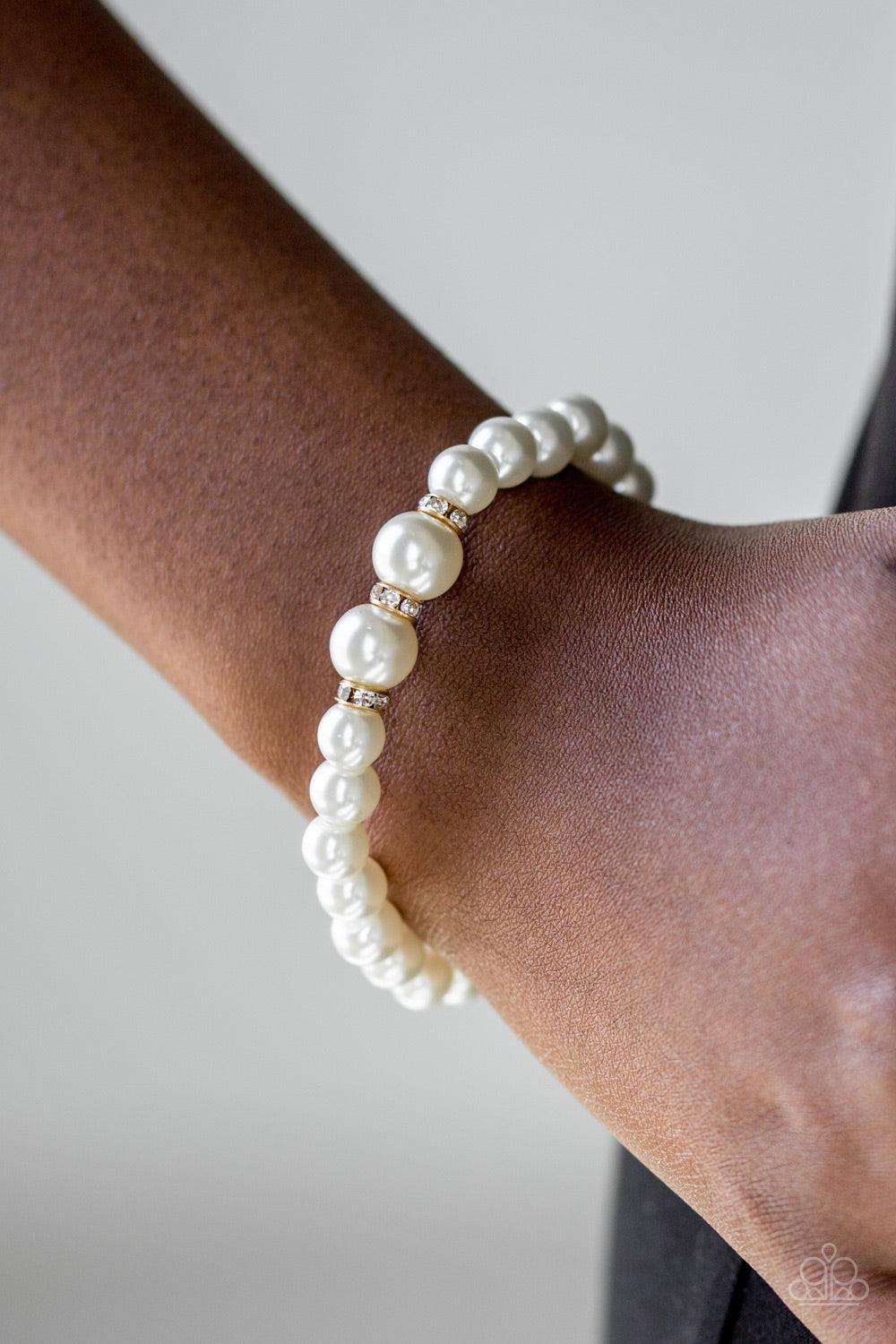 Paparazzi Accessories Radiantly Royal - White Gradually increasing in size near the center, luminescent white pearls are threaded along a stretchy elastic band. White rhinestone encrusted rings are sprinkled along the pearls for a timeless finish. Jewelry