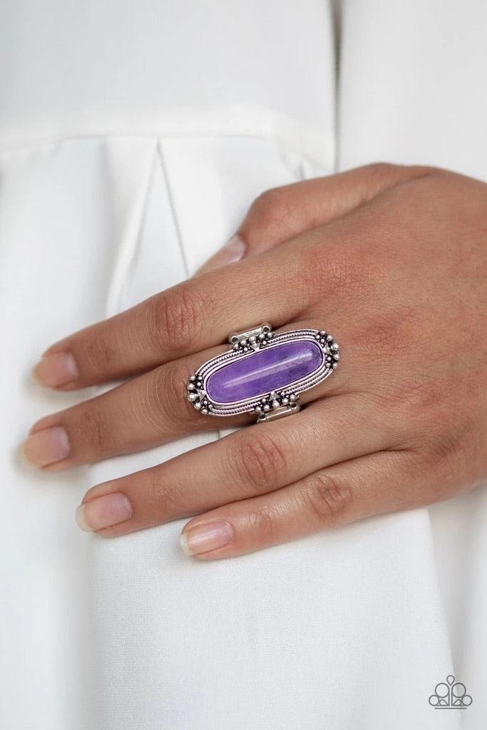 Paparazzi Accessories Desert Tranquility - Purple Featuring an oblong shape, a glassy purple stone bead is pressed into a studded silver frame atop the finger for a seasonal flair. Features a stretchy band for a flexible fit. Sold as one individual ring.