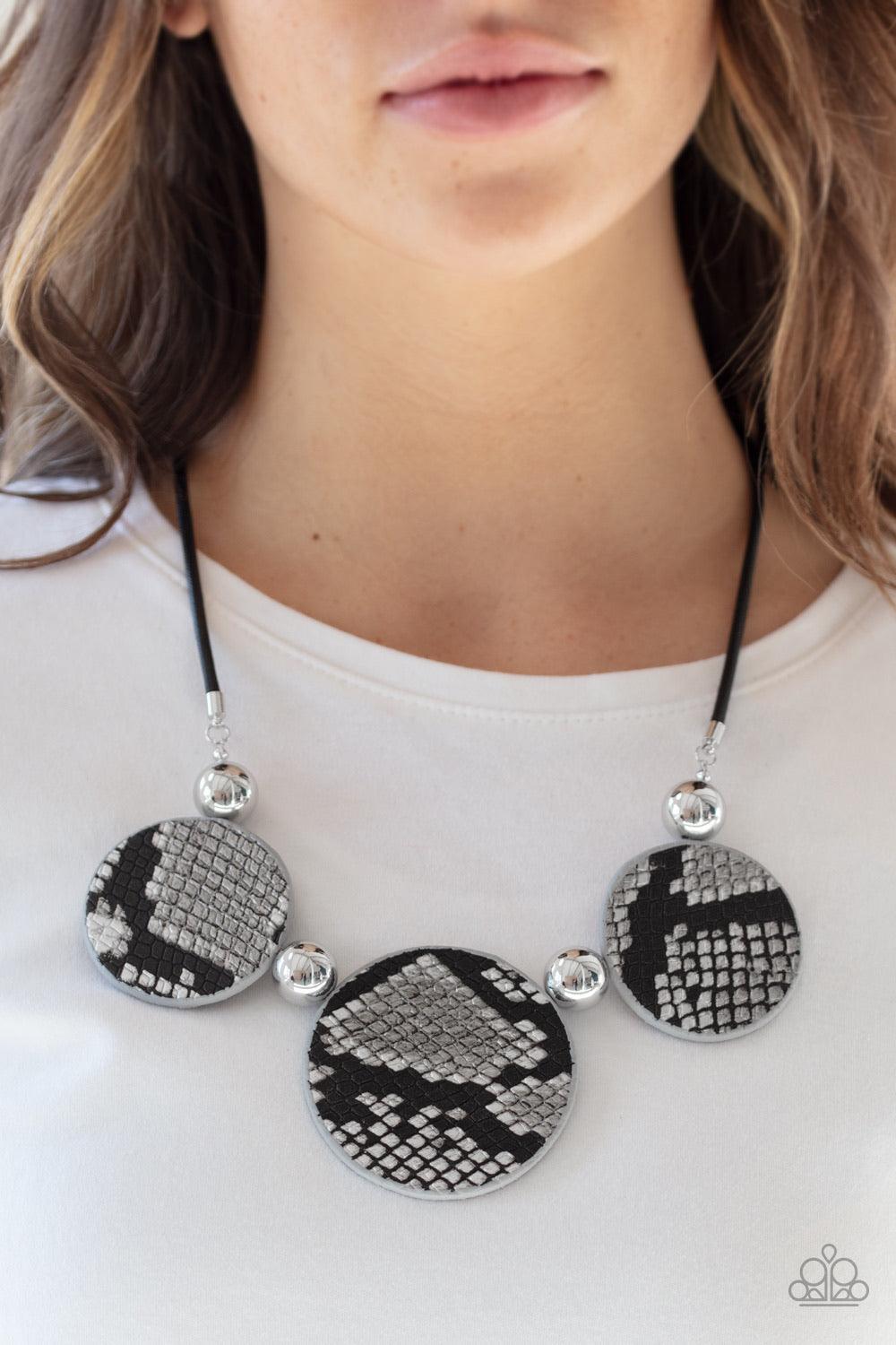 Paparazzi Accessories Viper Pit ~Black A wild collection of oversized silver beads and black and silver python patterned leather pieces are strung along an invisible wire below the collar for a statement-making finish. Features an adjustable clasp closure