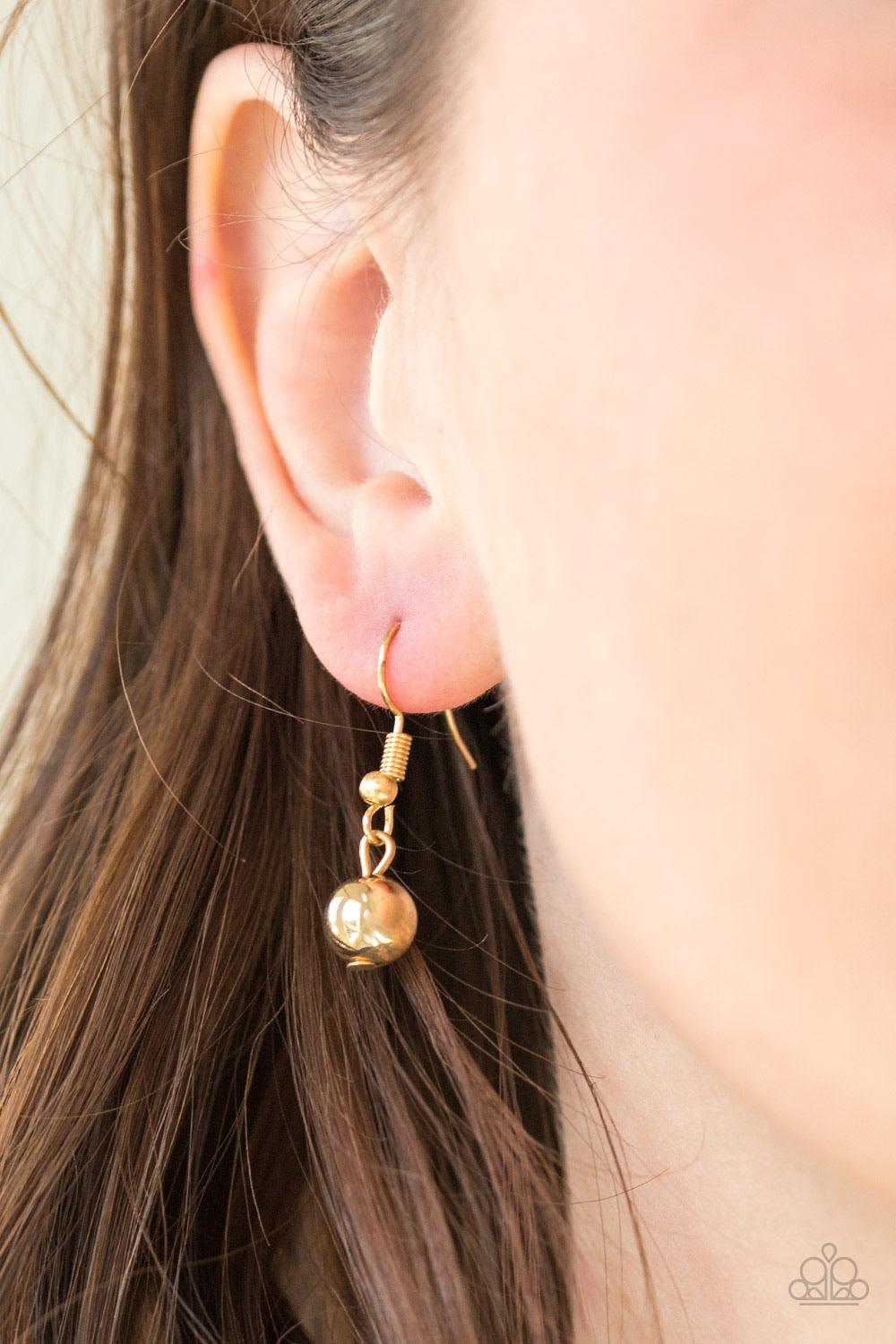 Paparazzi Accessories High-Stakes FAME - Gold Gradually increasing in size near the center, glistening gold beads are threaded along an invisible wire below the collar. Encrusted in glassy white rhinestones, a sparkling gold bead adorns the center for a r