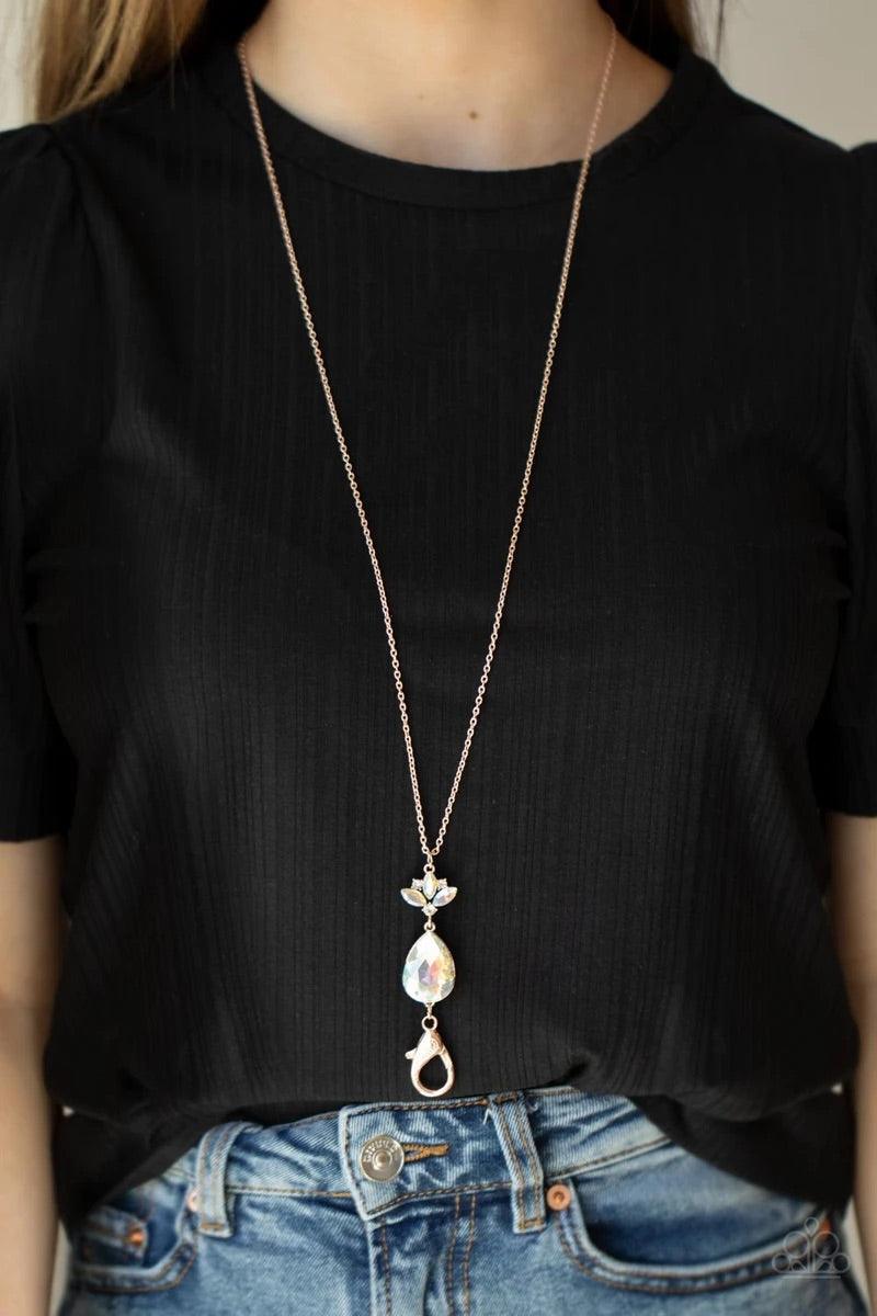 Paparazzi Accessories Divine Dazzle - Rose Gold Infused with a trio of glassy white rhinestones, a dainty frame of three marquise cut iridescent rhinestones give way to an oversized iridescent teardrop gem at the bottom of a lengthened rose gold chain for