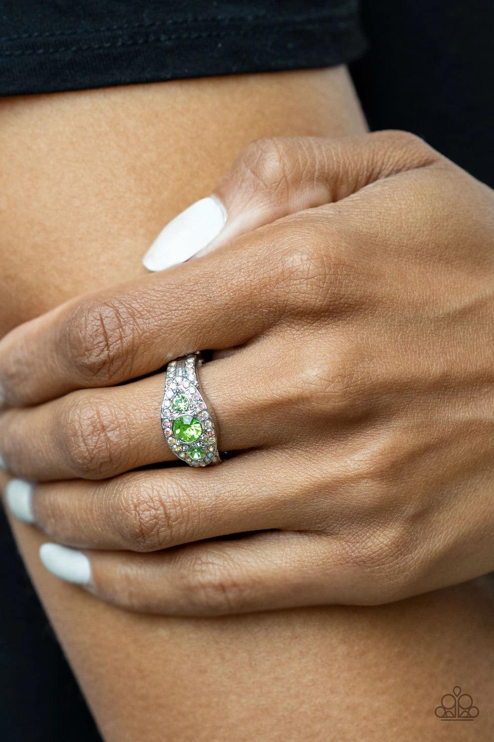Paparazzi Accessories Celestial Crowns - Green A trio of brilliant green rhinestones is set inside a glittering rhinestone-encrusted frame creating a divinely heavenly essence atop the finger. Features a dainty stretchy band for a flexible fit. Sold as on
