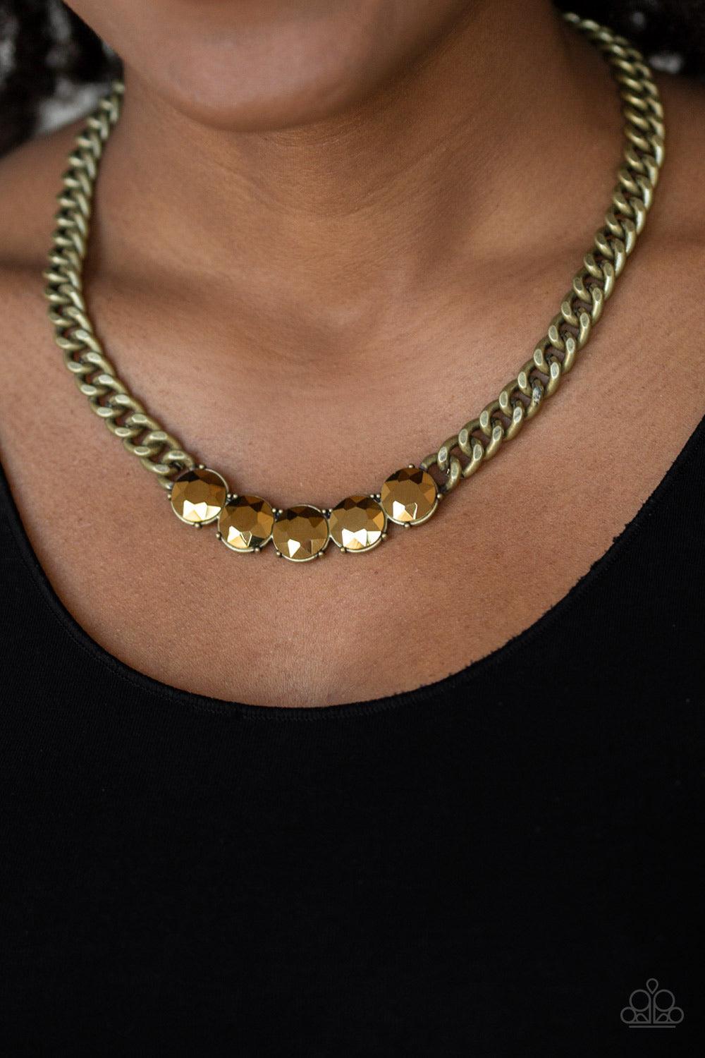 Paparazzi Accessories Rhinestone Renegade - Brass A thick brass chain gives way to a dramatic row of glittery aurum rhinestones, creating a bold and blinding statement below the collar. Features an adjustable clasp closure. Jewelry