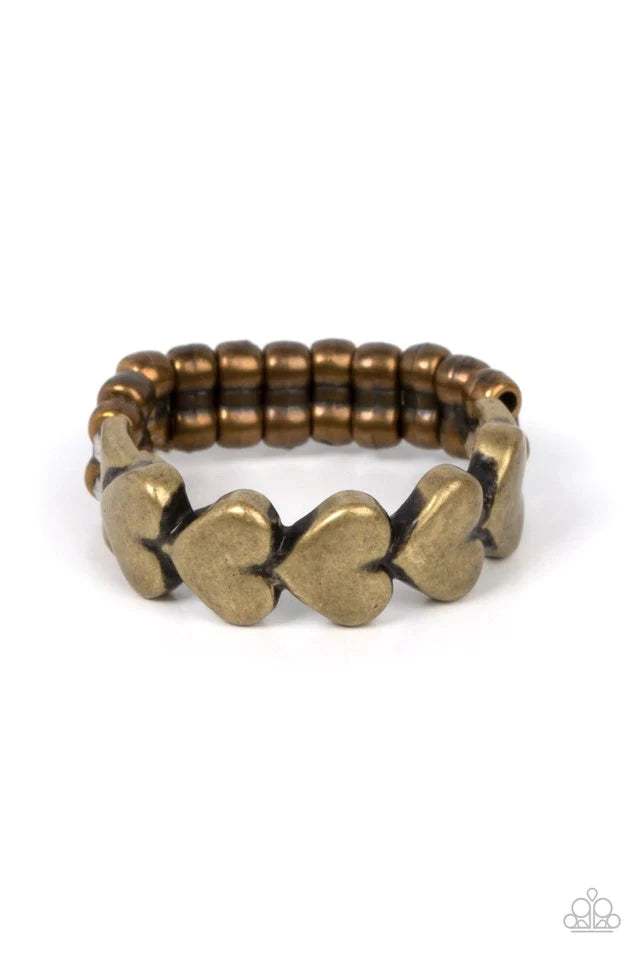 Paparazzi Accessories Rhythm of Love - Brass Brushed in an antiqued shimmer, a dainty row of brass heart frames repeats across the finger for a rustically romantic flair. Features a dainty stretchy band for a flexible fit. Jewelry