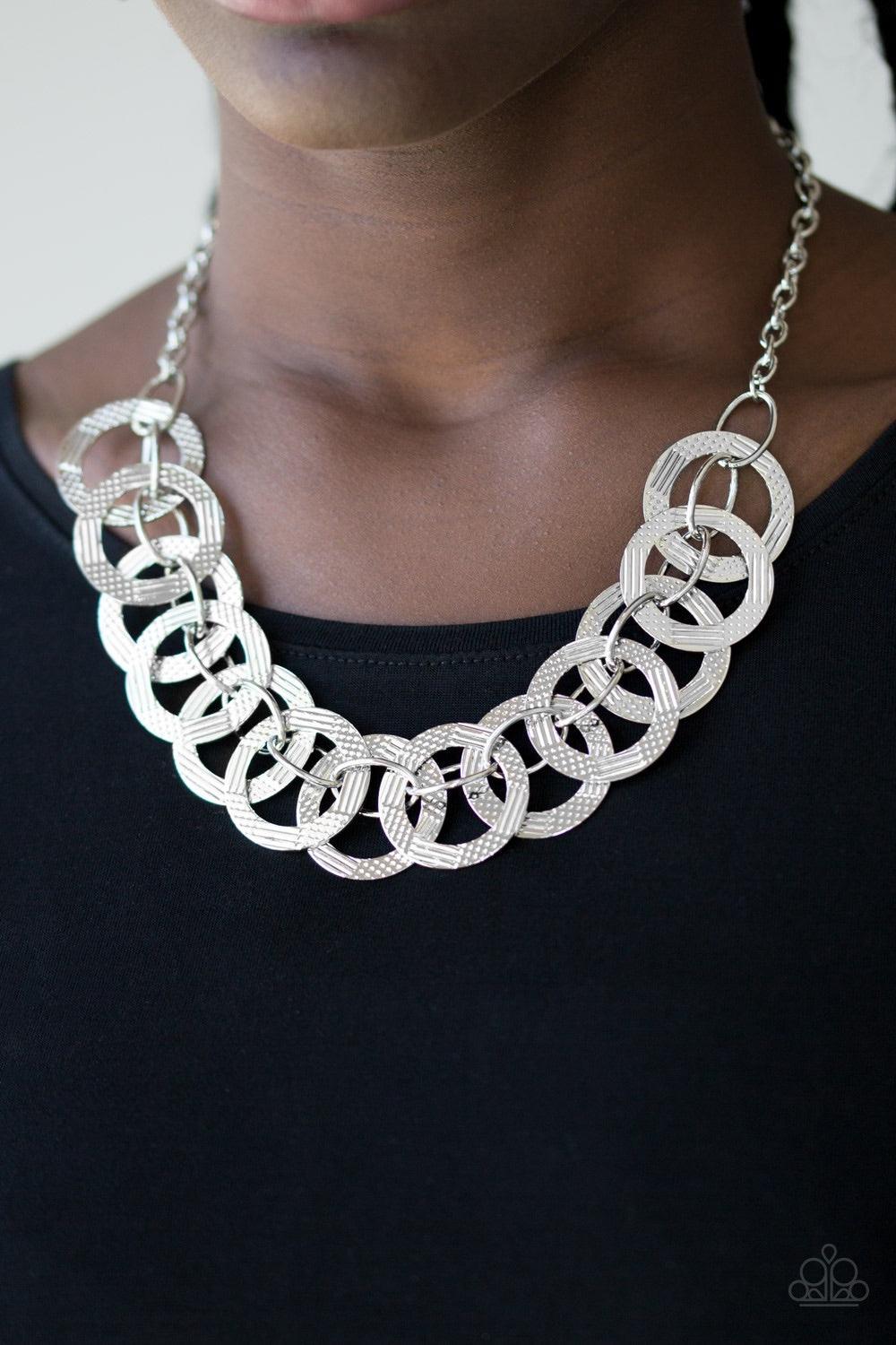 Paparazzi Accessories The Main Contender - Silver Etched and hammered in linear and diamond-cut shimmer, glistening silver circles interlock into a bold industrial chain below the collar. Features an adjustable clasp closure Jewelry