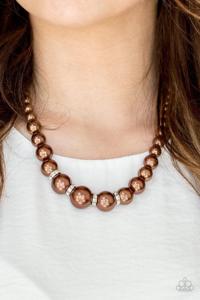 Paparazzi Accessories Party Pearls - Brown Gradually increasing in size, luminescent brown pearls trickle below the collar for a classic look. Encrusted in dazzling white rhinestones, glittery rings are sprinkled between the pearls for a timeless finish.
