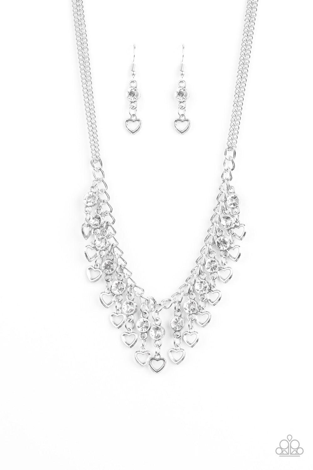 Paparazzi Accessories Valentines Day Drama ~White A row of shimmery silver hearts and glittery white rhinestones swing from the bottom of a glistening silver fringe, creating a flirty fringe below the collar. Features an adjustable clasp closure. Sold as
