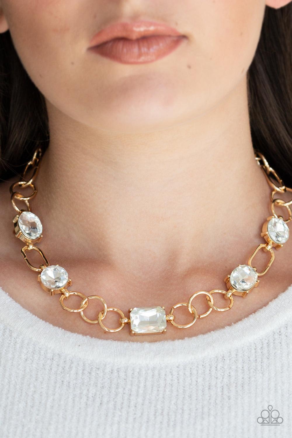 Paparazzi Accessories Urban District ~Gold Featuring round, oval, and emerald style cuts, glittery white rhinestone fittings link with mismatched gold rings below the collar for an edgy glamorous look. Features an adjustable clasp closure.